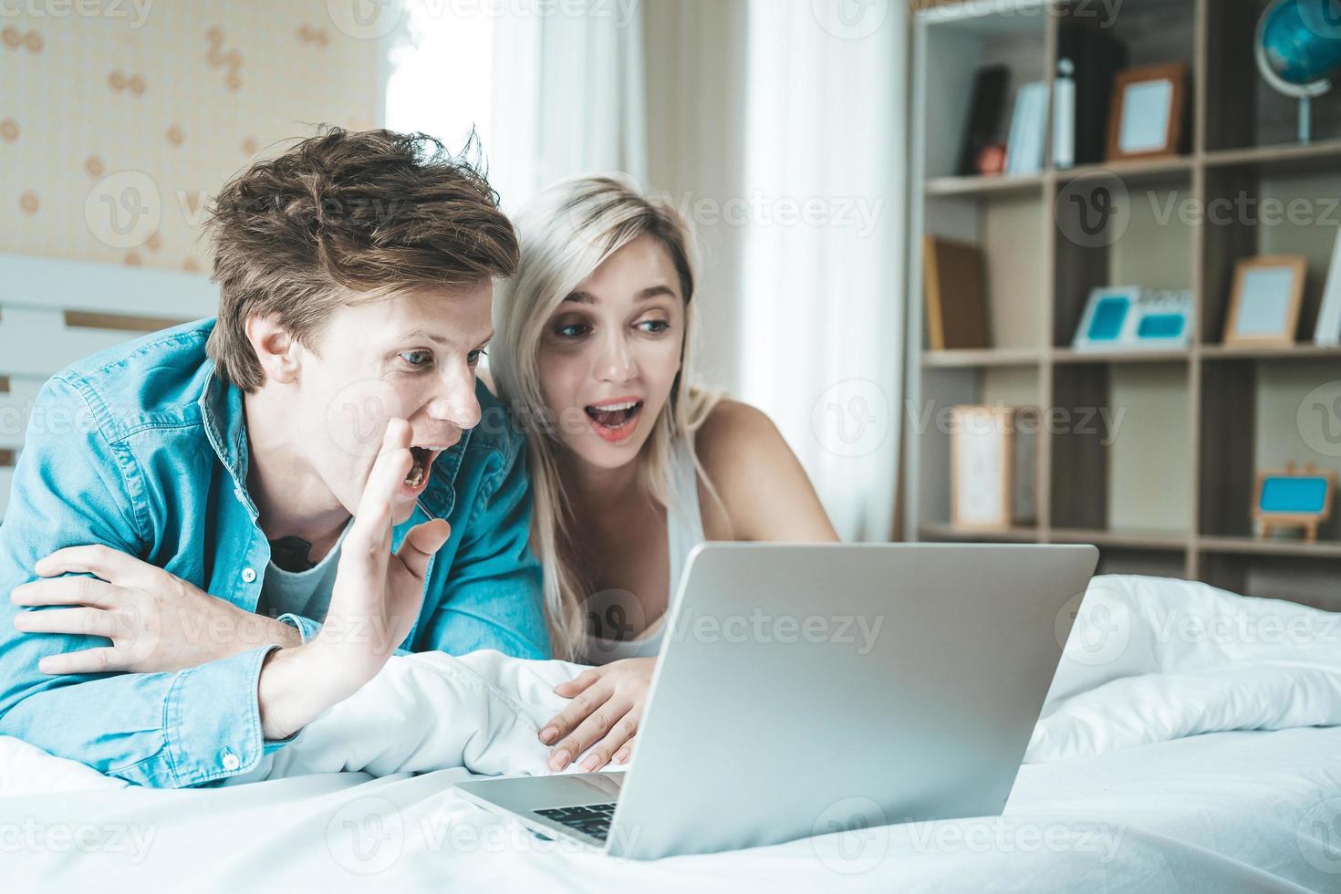 casal feliz usando laptop na cama foto