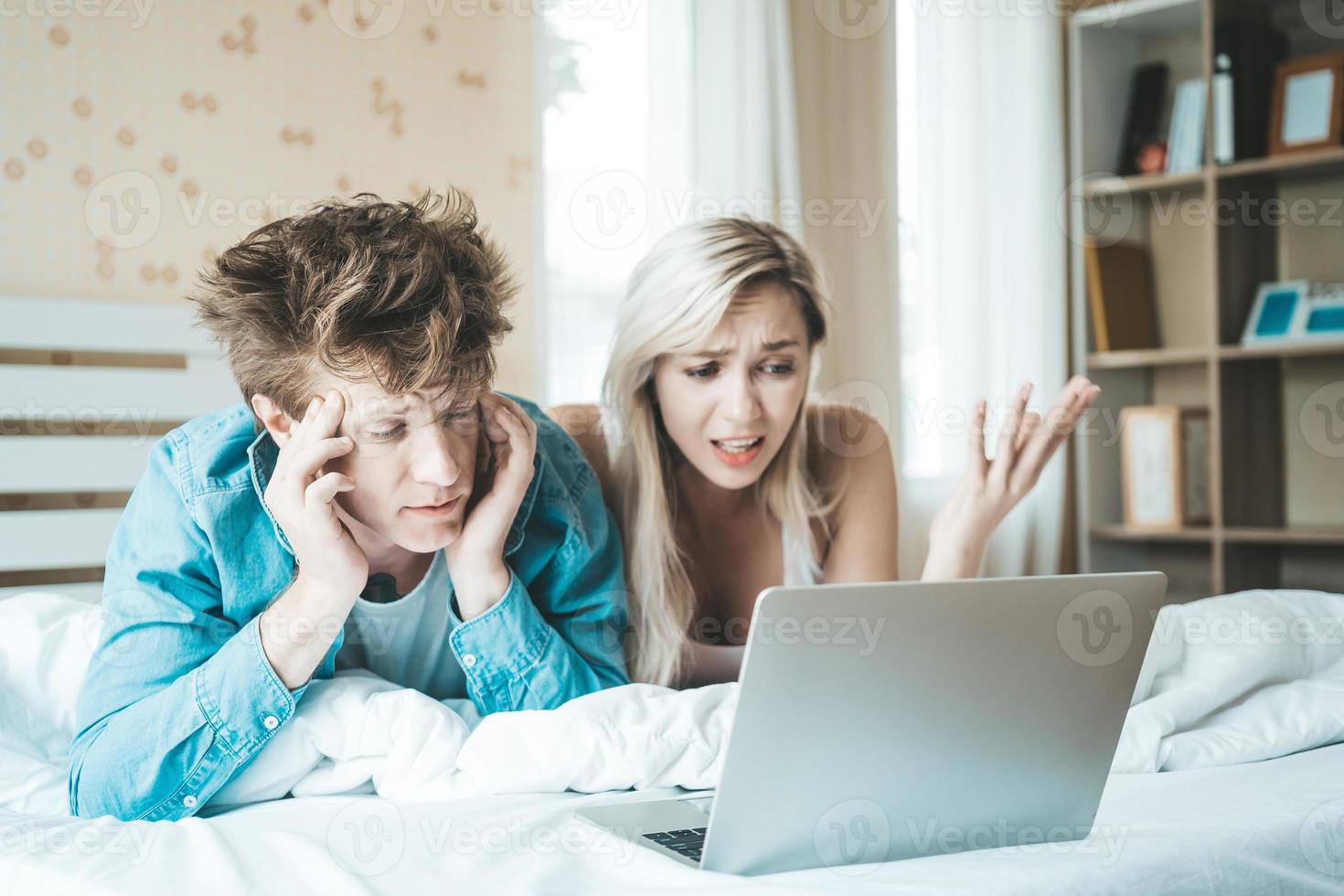 casal feliz usando laptop na cama foto