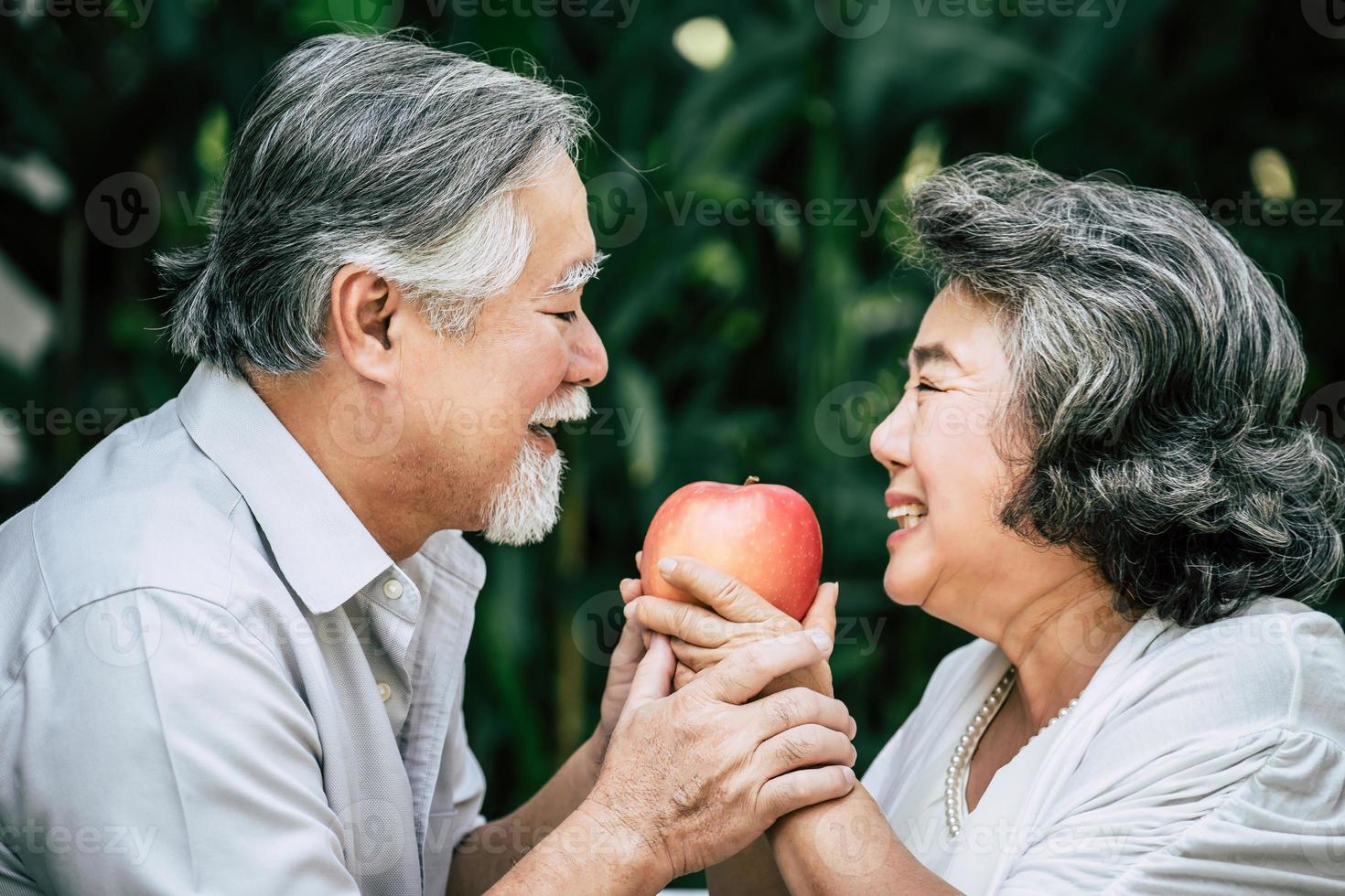 casal de idosos brincando e comendo frutas foto