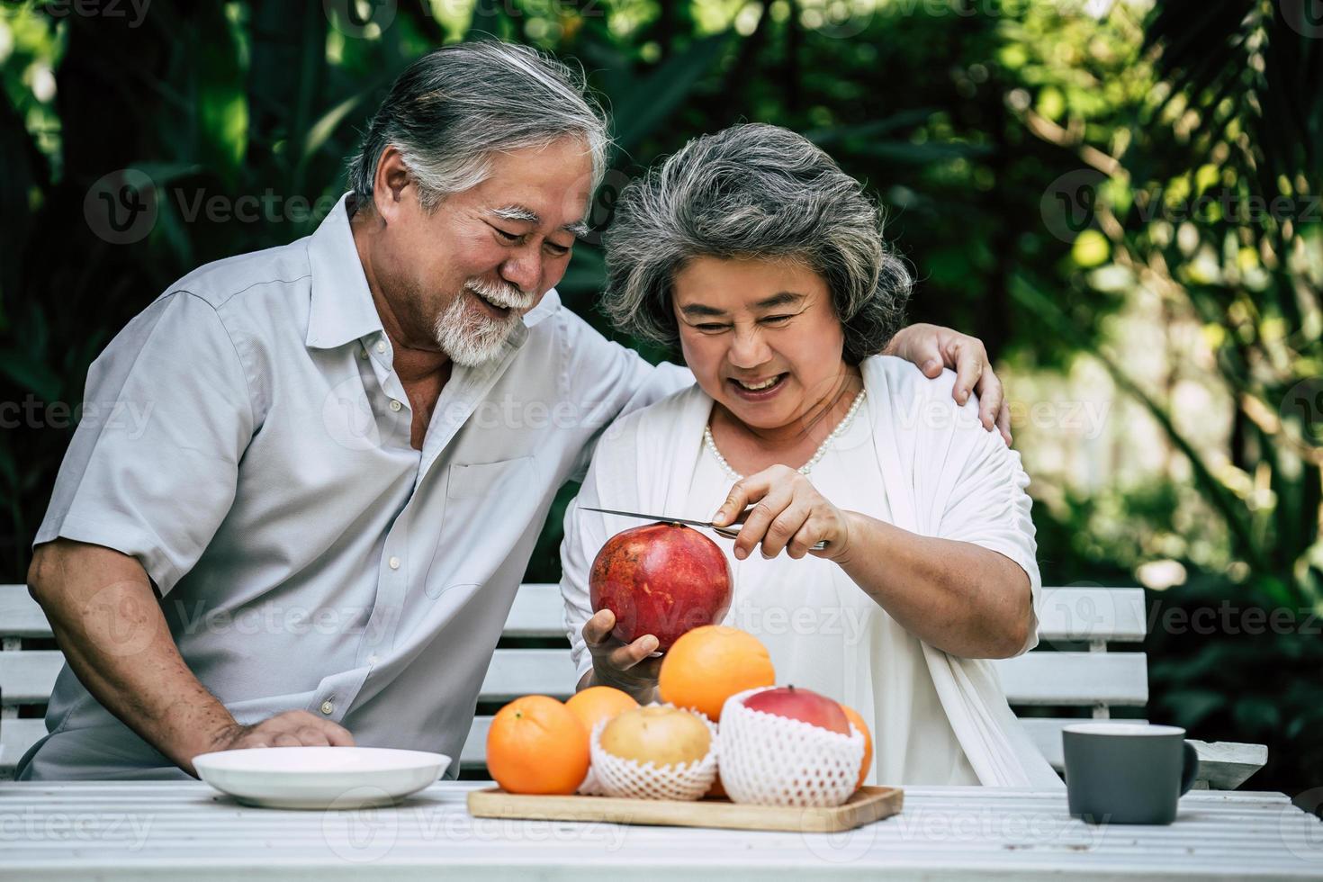 casal de idosos brincando e comendo frutas foto