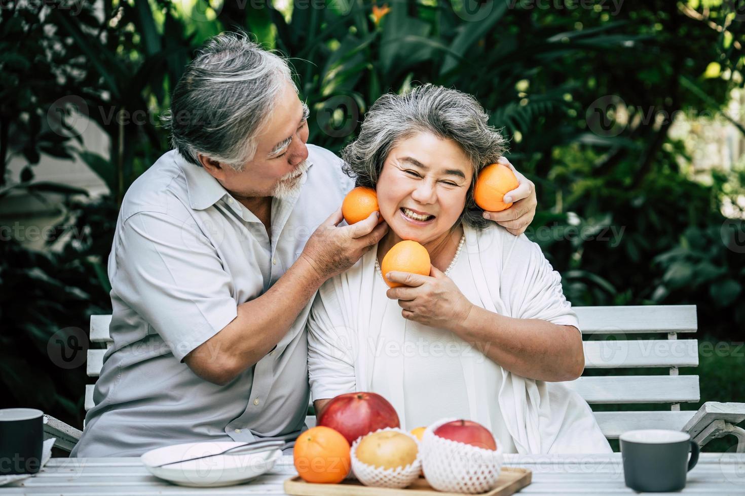 casal de idosos brincando e comendo frutas foto