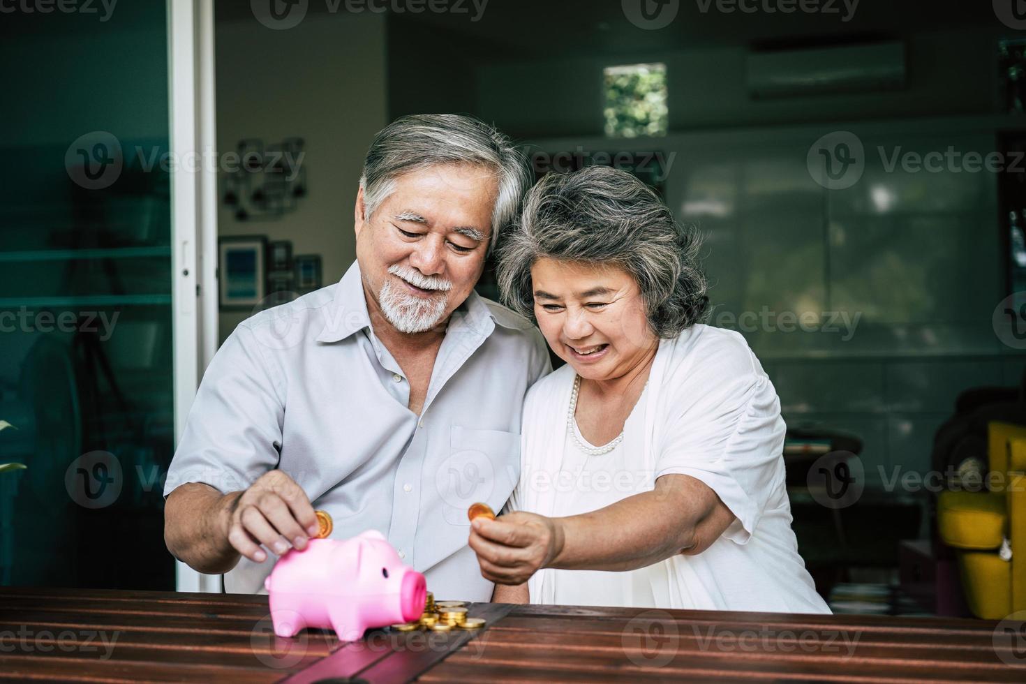 casal de idosos conversando sobre finanças com o cofrinho foto