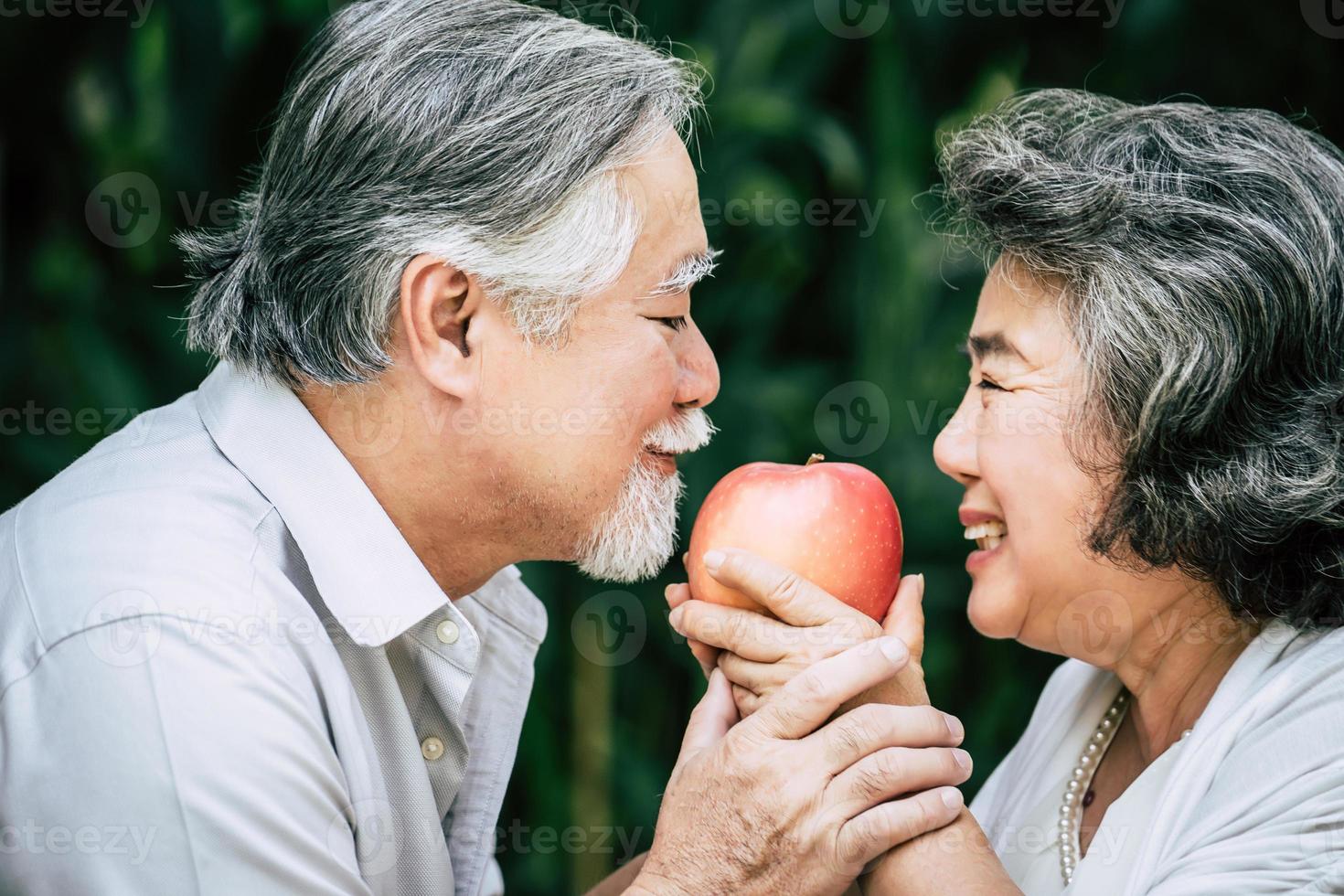 casal de idosos brincando e comendo frutas foto