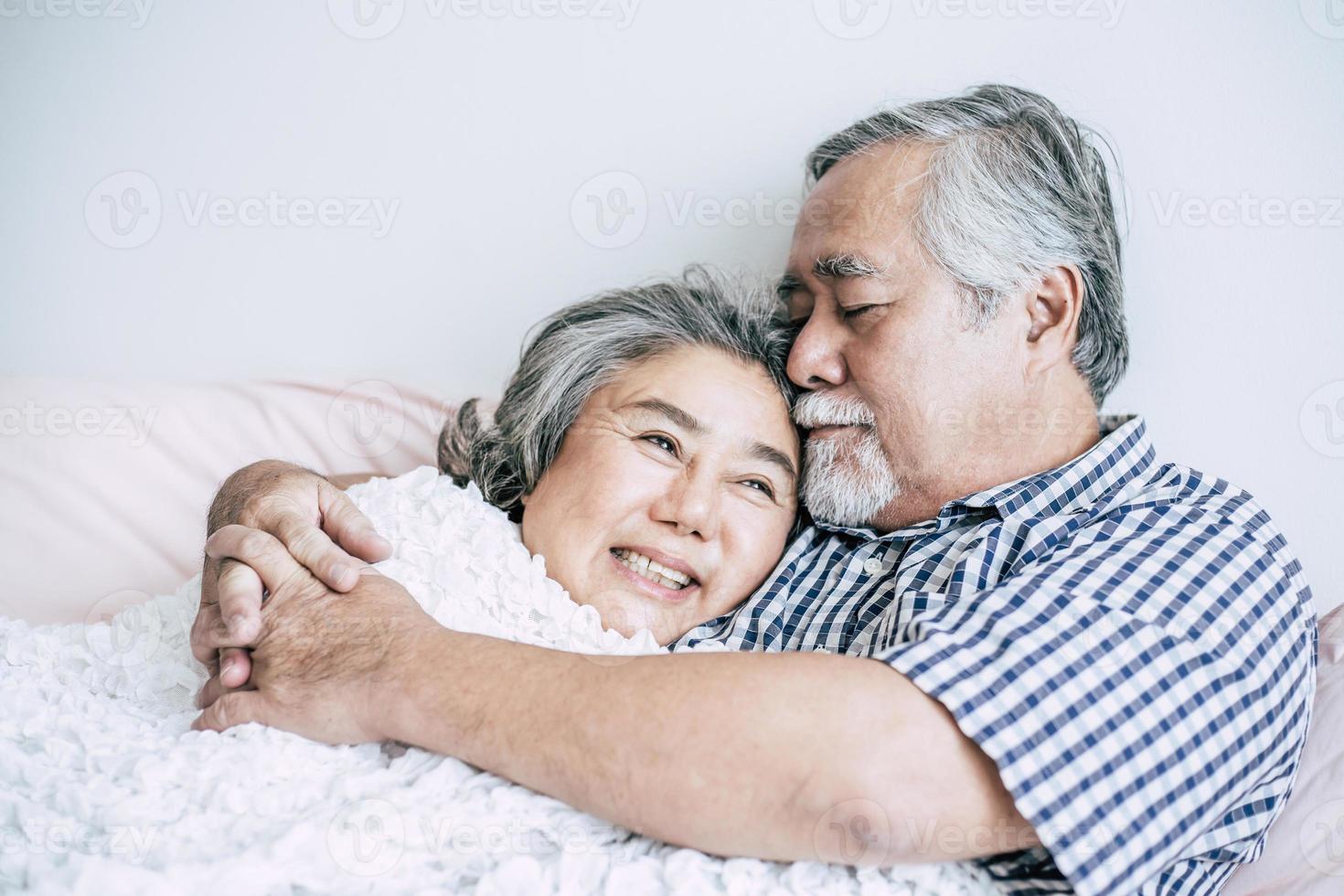 casal de idosos deitado na cama juntos foto