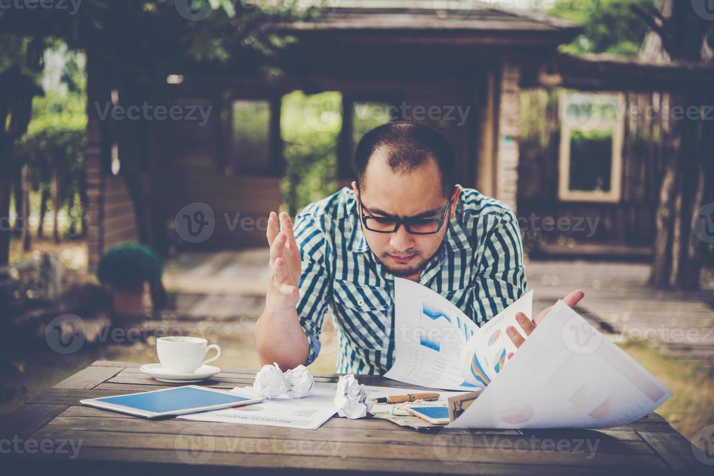 empresário estressado com papéis e gráficos sentado à mesa em casa foto