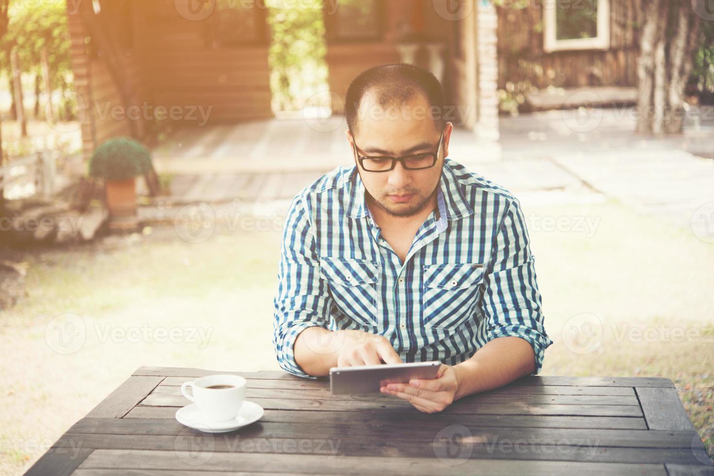empresário trabalha em tablet enquanto está sentado à mesa de madeira em casa foto