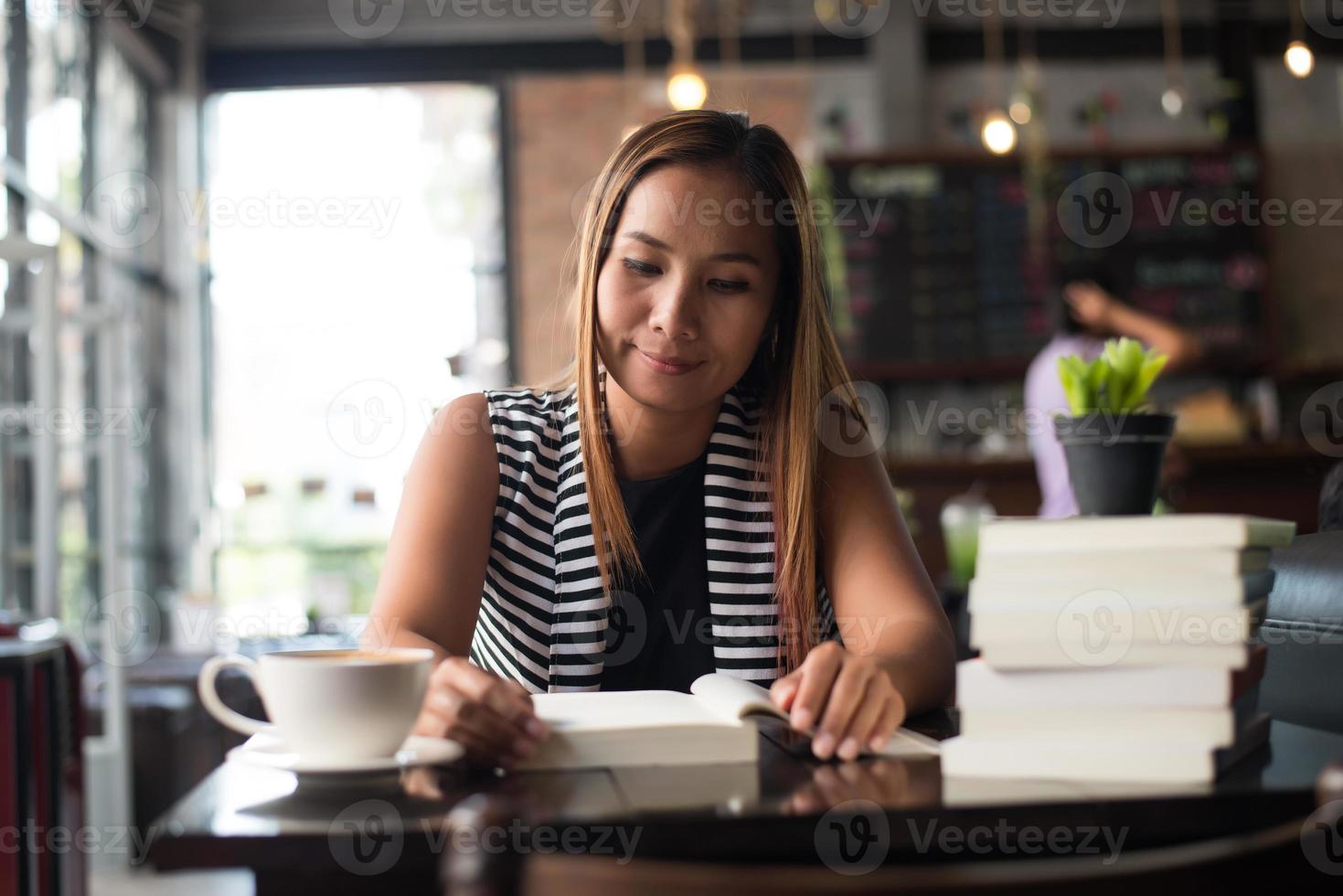 mulher asiática relaxando e lendo um livro no café foto