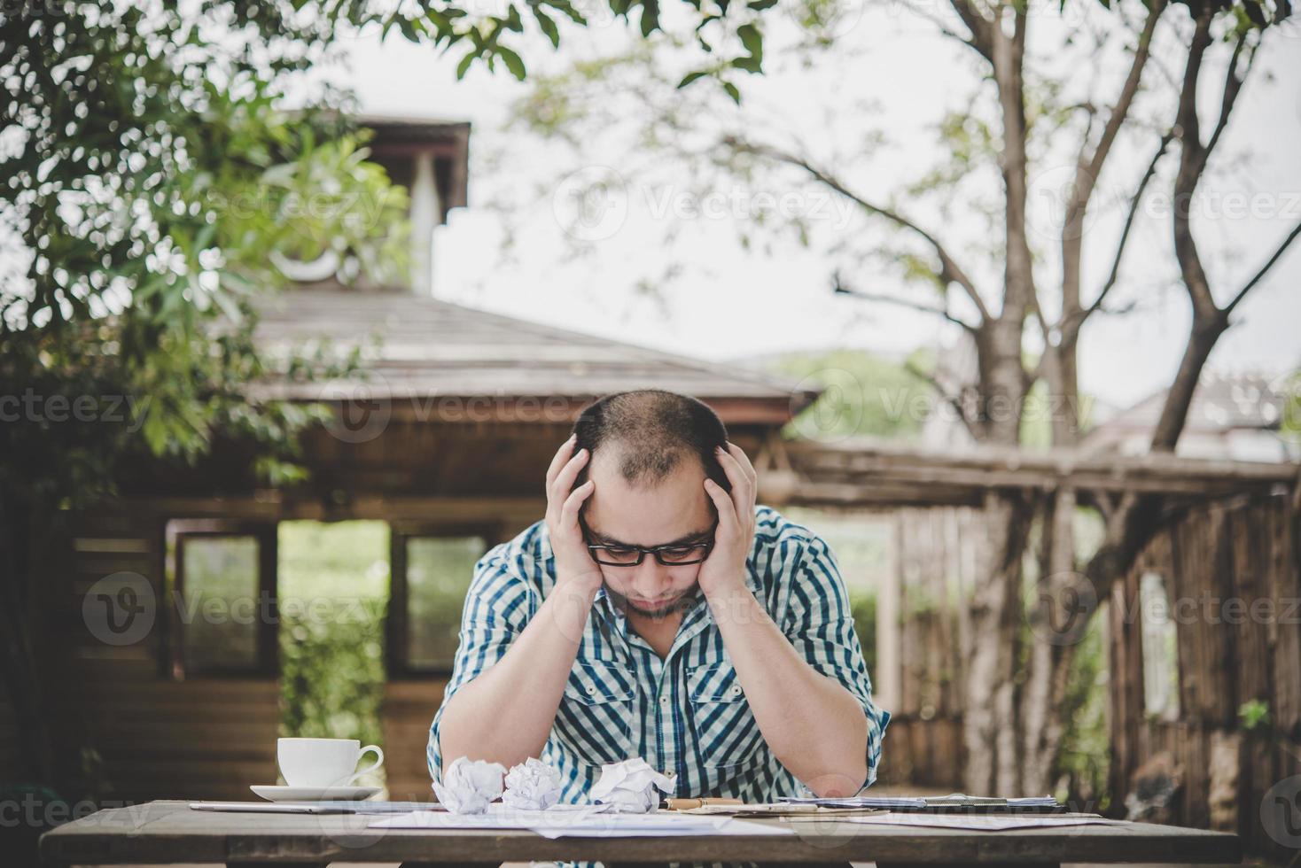 empresário estressado com papéis e gráficos sentado à mesa em casa foto