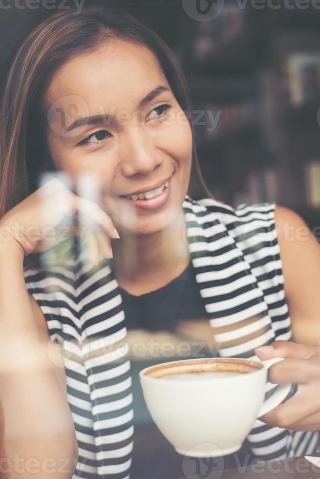 mulher asiática relaxando com um café no café foto