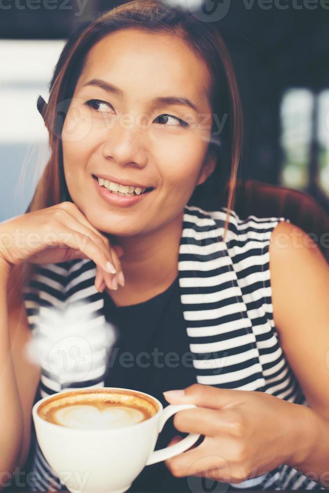 mulher asiática relaxando com um café no café foto