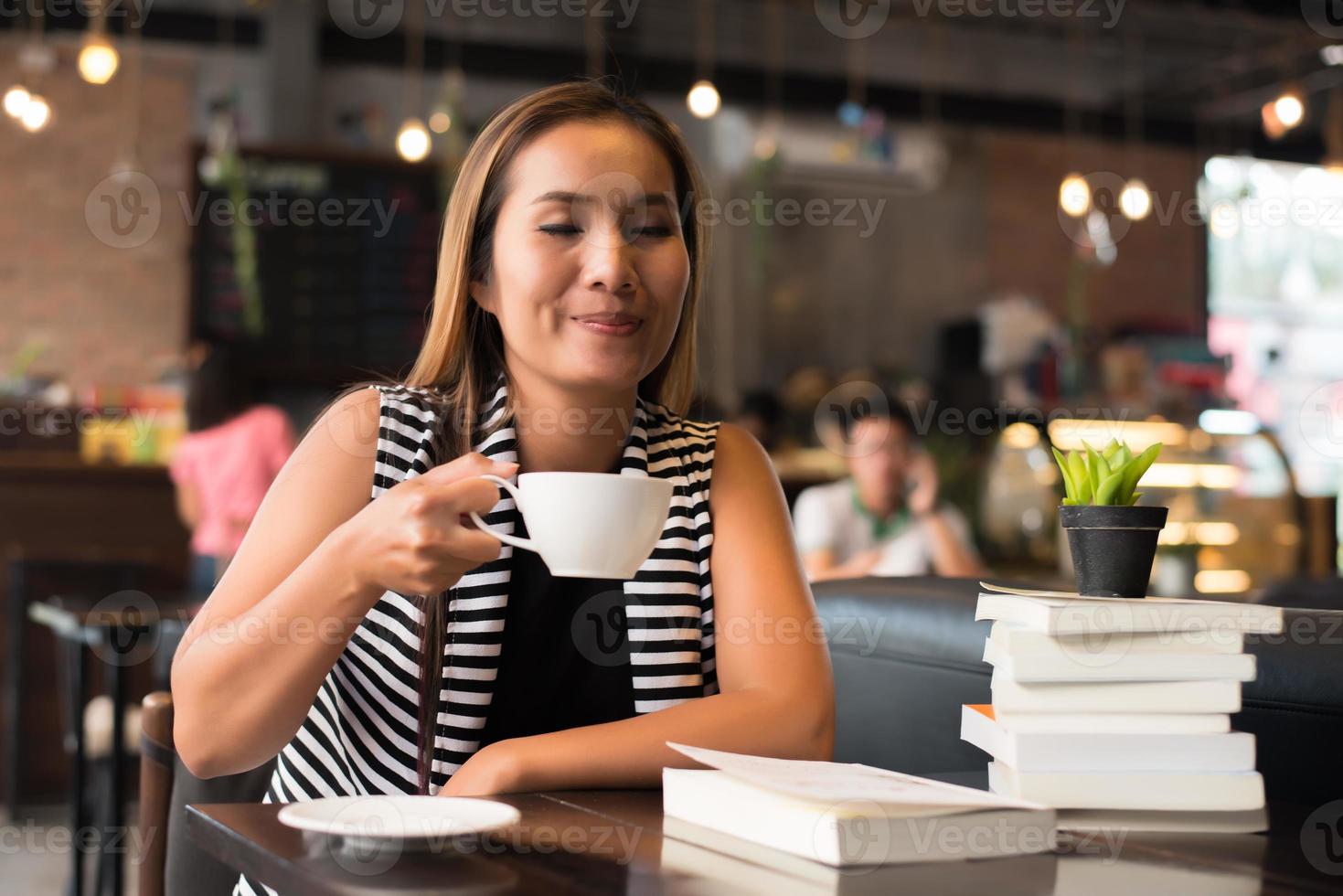 mulher asiática relaxando e lendo um livro no café foto