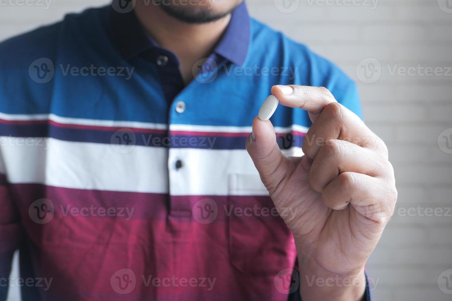 homem segurando uma pílula branca foto