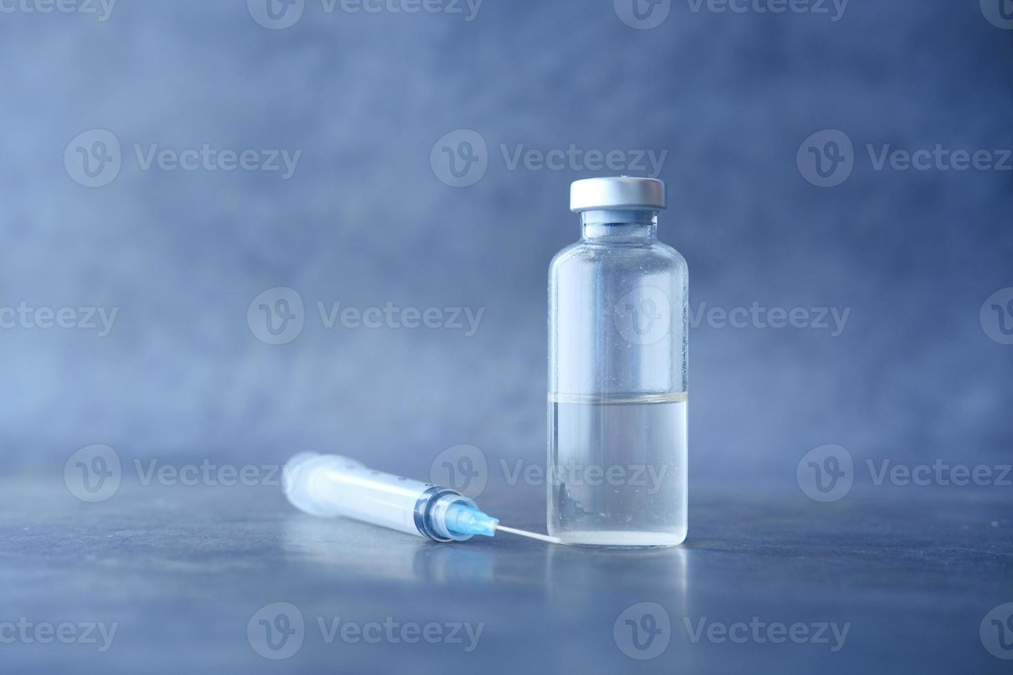 close-up de uma vacina e seringa em fundo preto foto