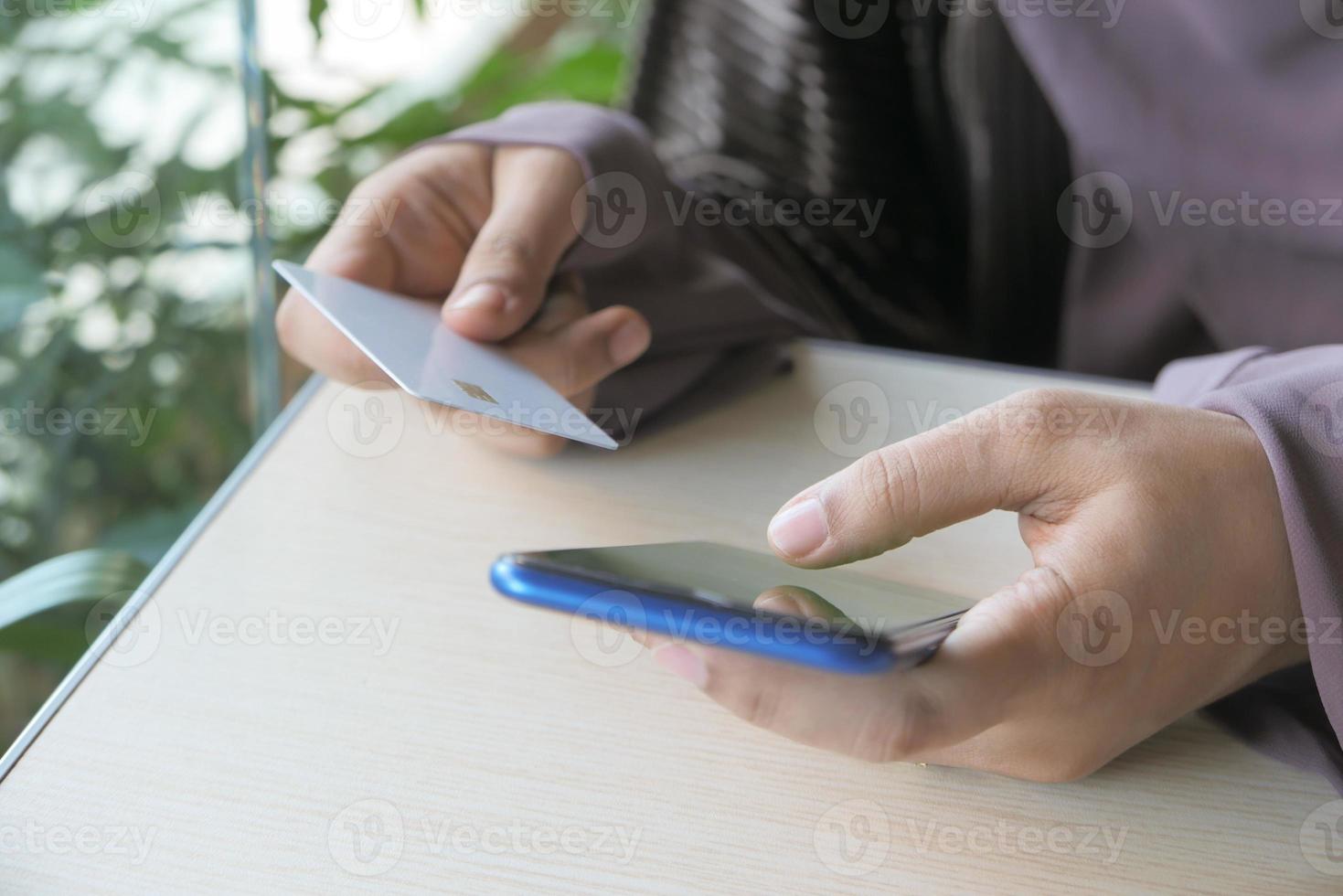 mulher segurando um cartão de crédito e usando um telefone inteligente para fazer compras online foto