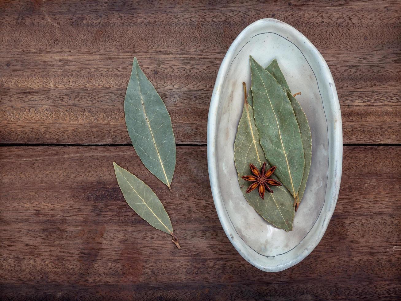 folhas de louro em uma tigela de cerâmica sobre uma mesa foto