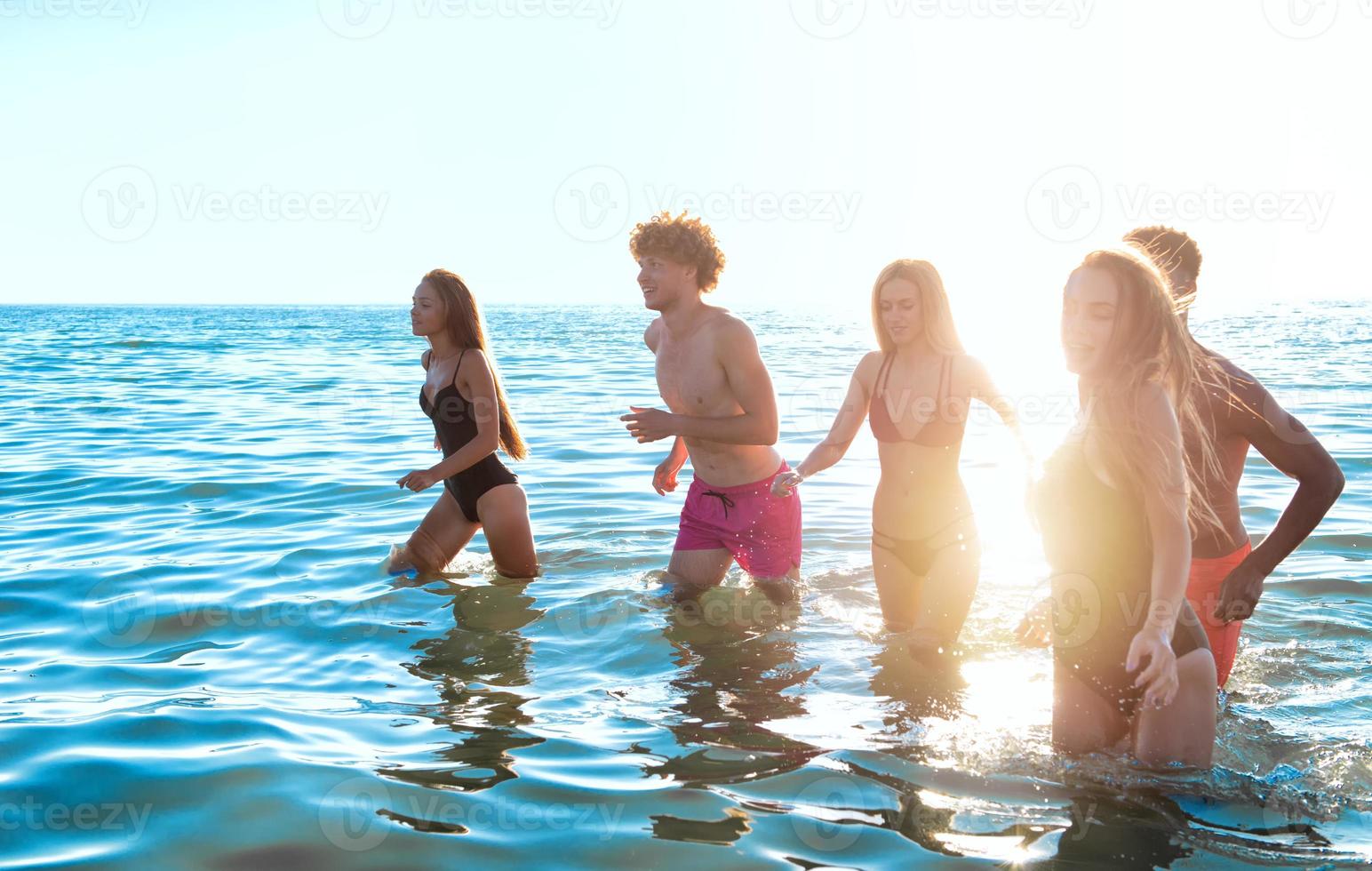 grupo do amigos corre dentro a mar. conceito do horário de verão foto