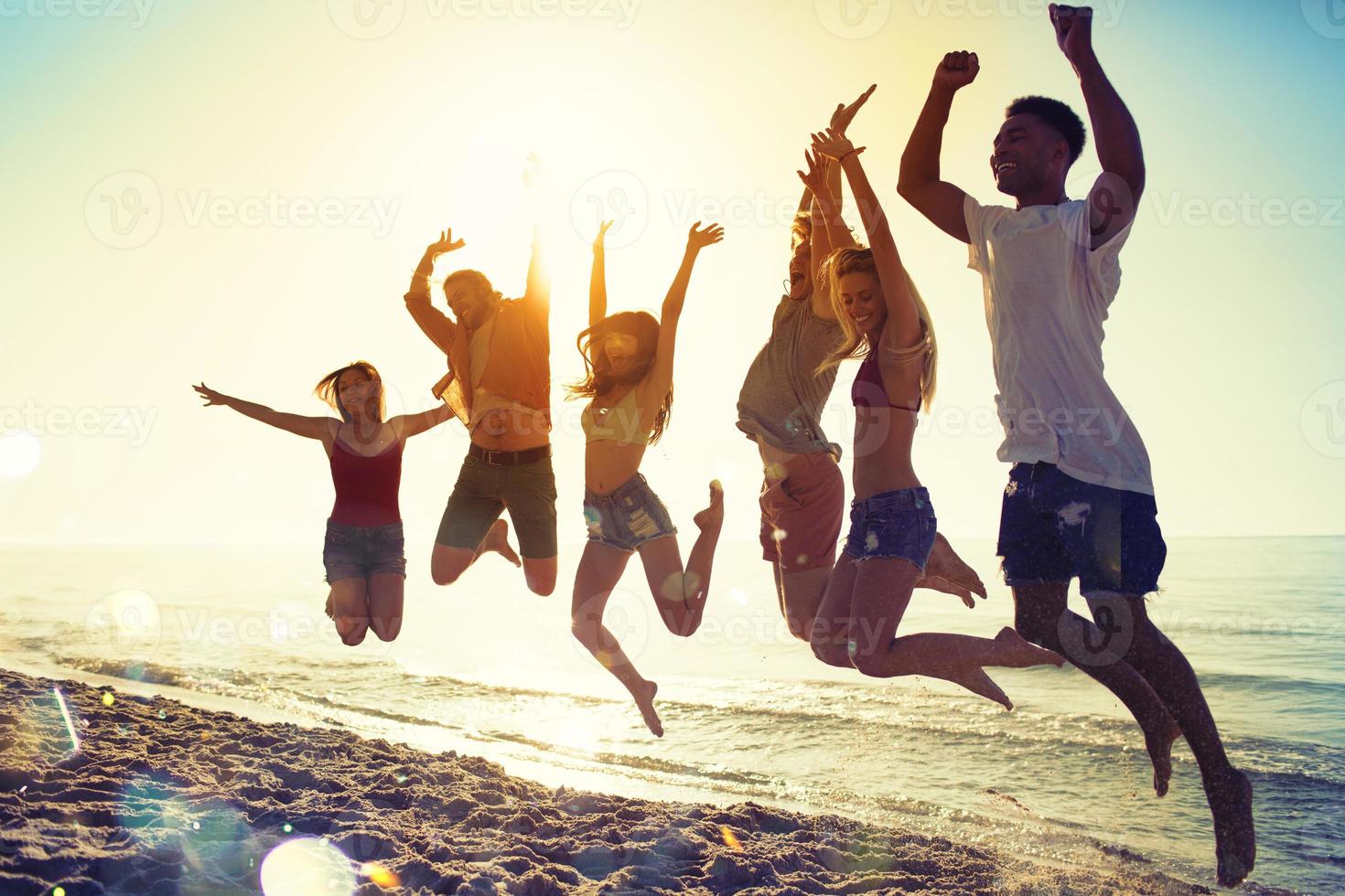 feliz sorridente amigos pulando às a de praia foto