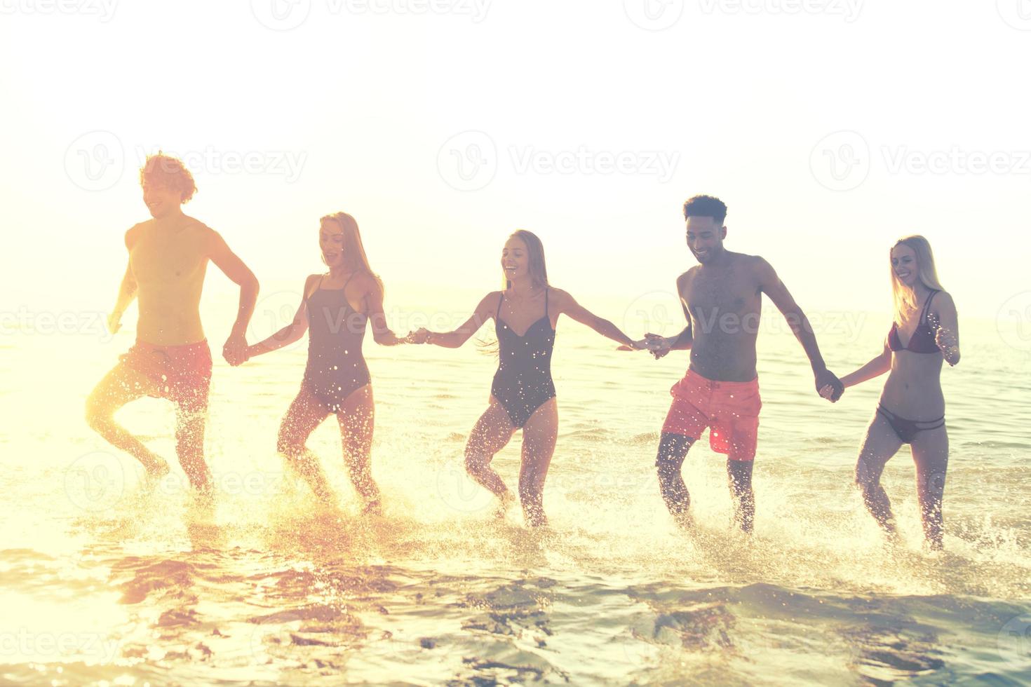 grupo do amigos corre dentro a mar. conceito do horário de verão foto