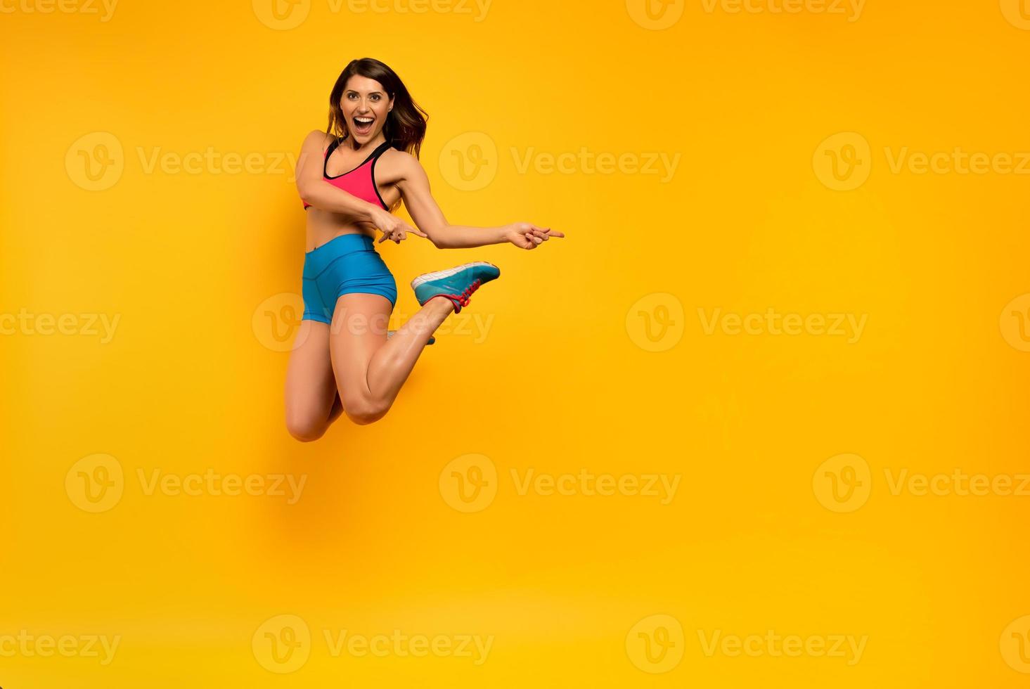 esporte mulher saltos em uma amarelo fundo. feliz e alegre expressão. foto