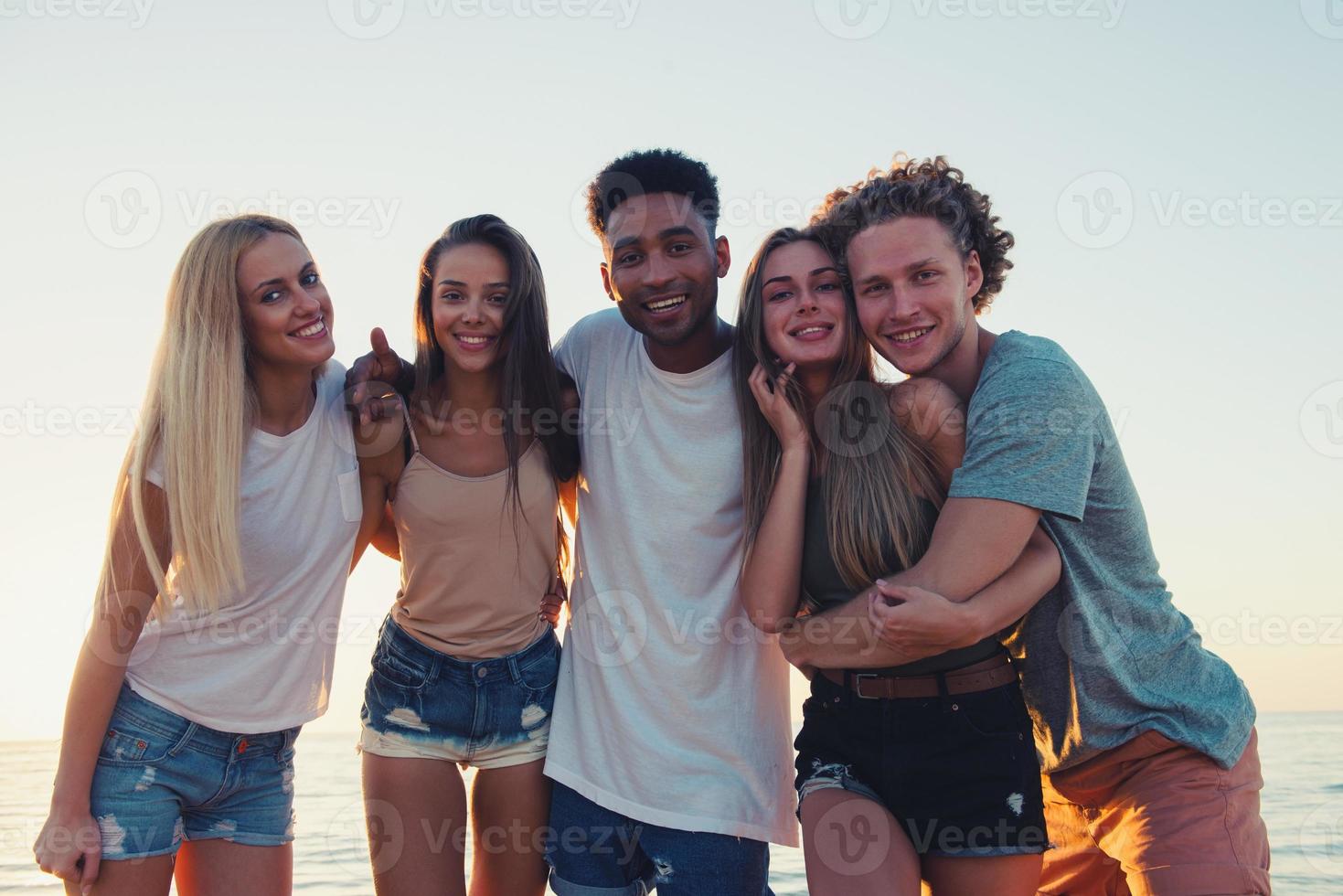 grupo do feliz amigos tendo Diversão às oceano de praia foto