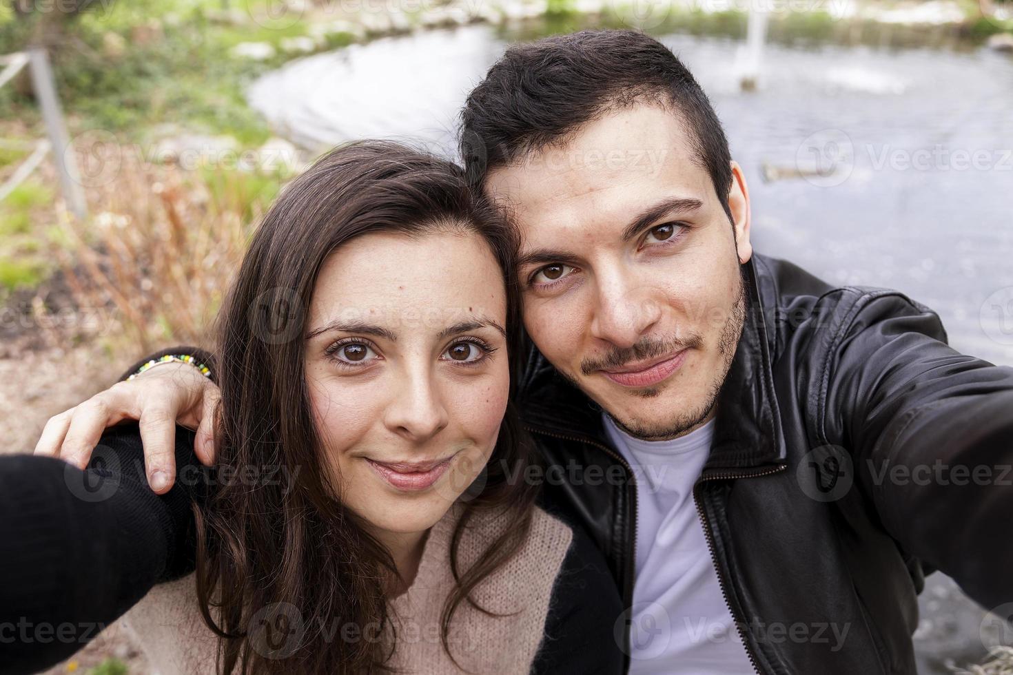 agradável casal namorados dentro a parque leva uma selfie foto