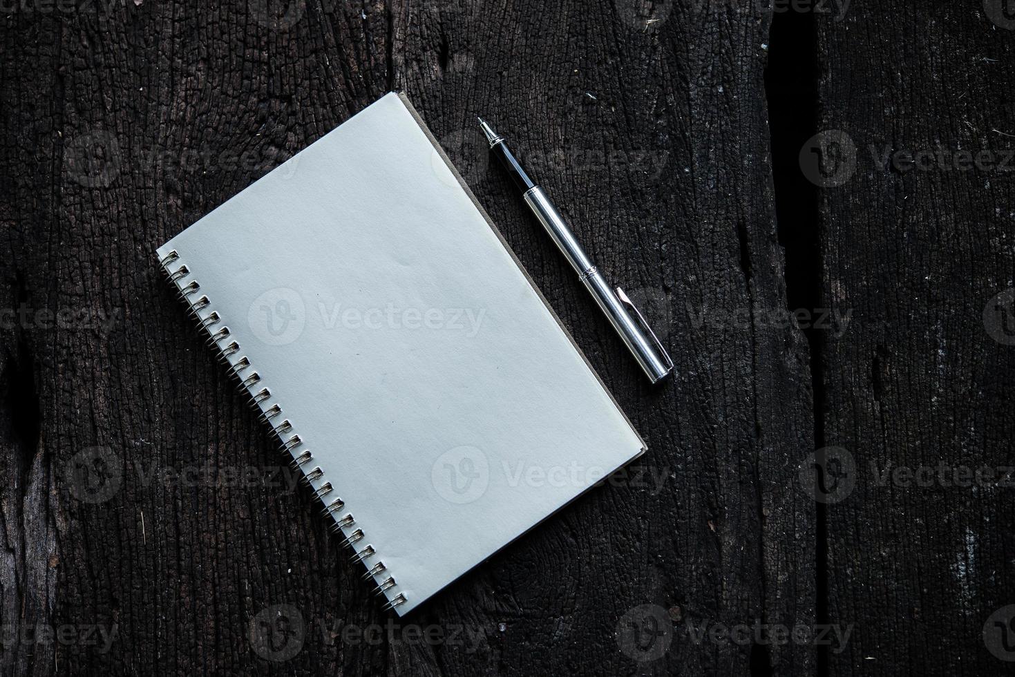 caderno com caneta em fundo de textura de madeira foto
