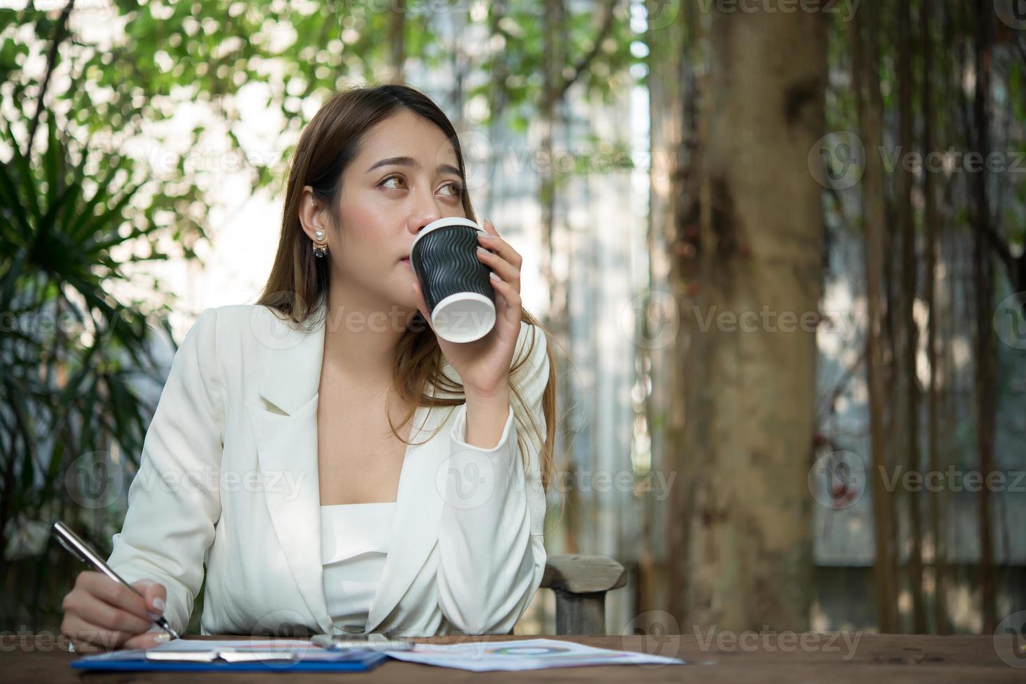 jovem empresária sentada em um escritório tomando uma xícara de café foto