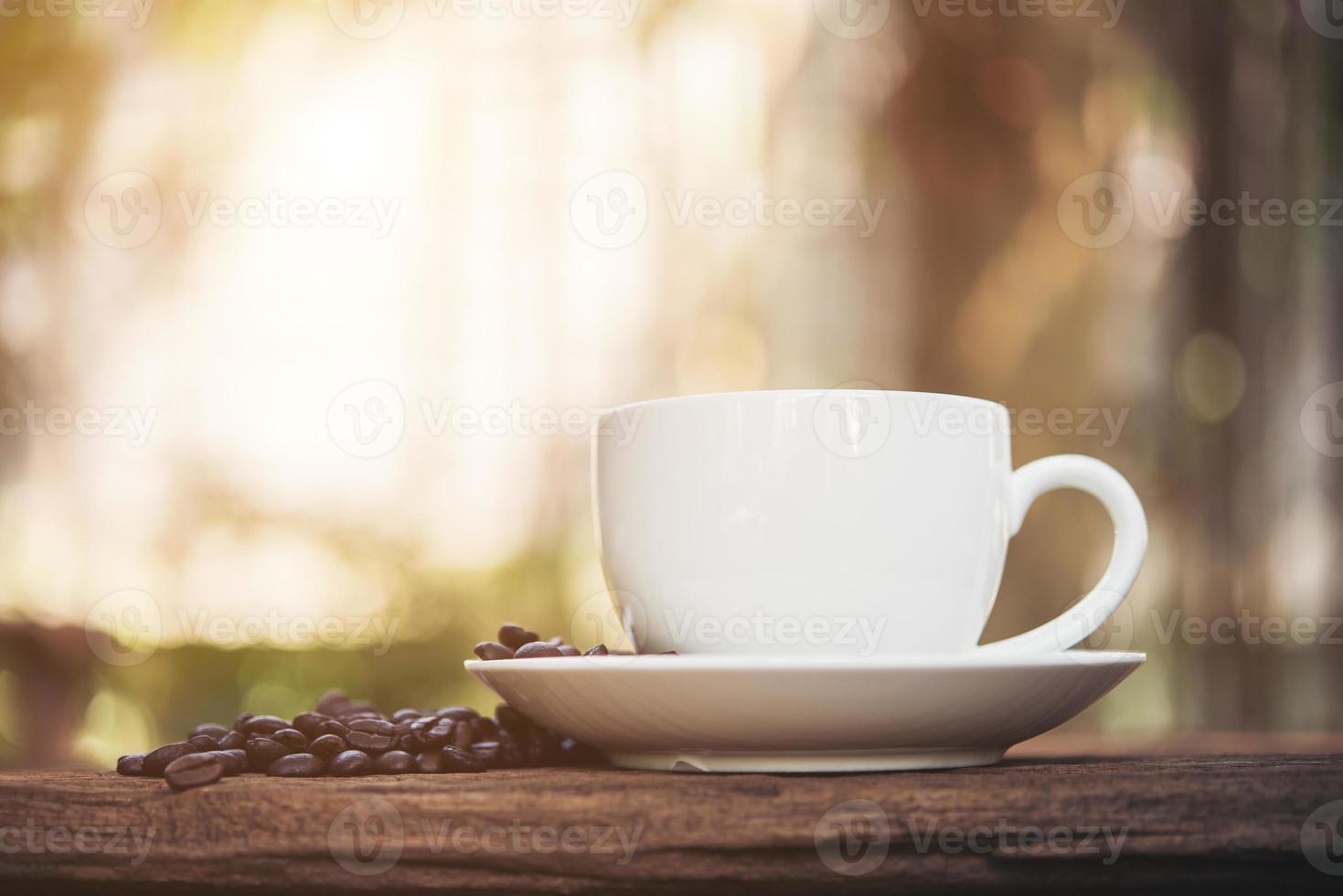 xícara de café e grãos de café na mesa de madeira foto