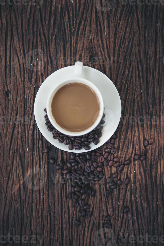 vista superior da xícara de café e grãos de café na mesa de madeira foto