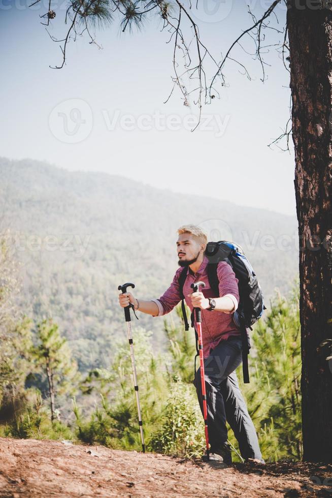 homem viajante com mochila olhando para o mapa enquanto pratica alpinismo foto