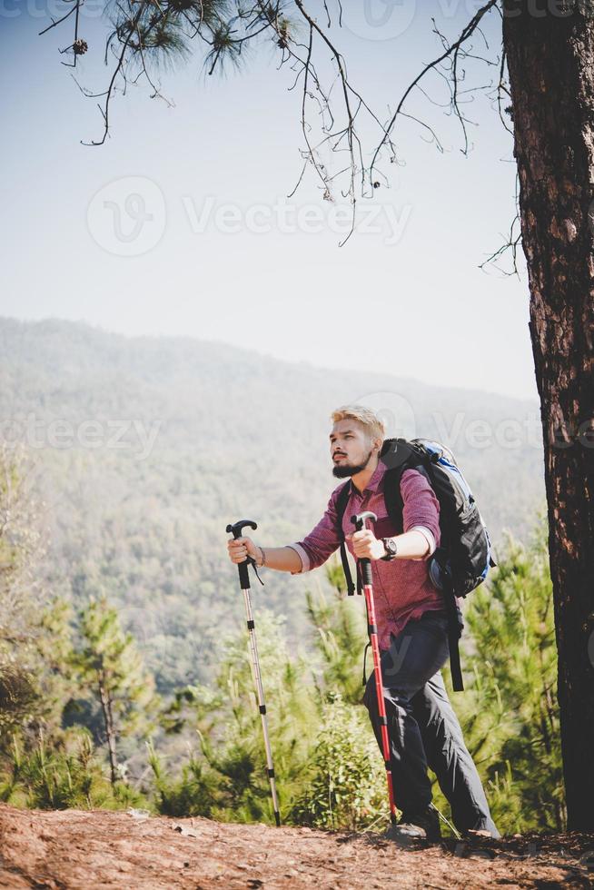 homem viajante com mochila olhando o mapa enquanto pratica alpinismo foto