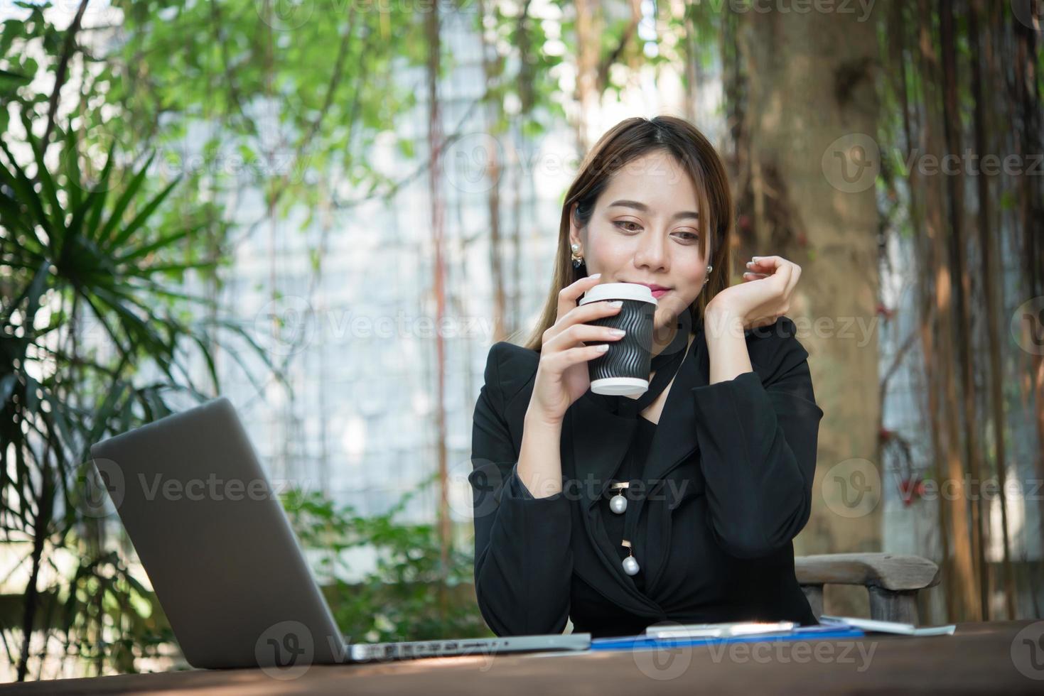 jovem mulher de negócios tomando café durante o trabalho em um laptop portátil foto