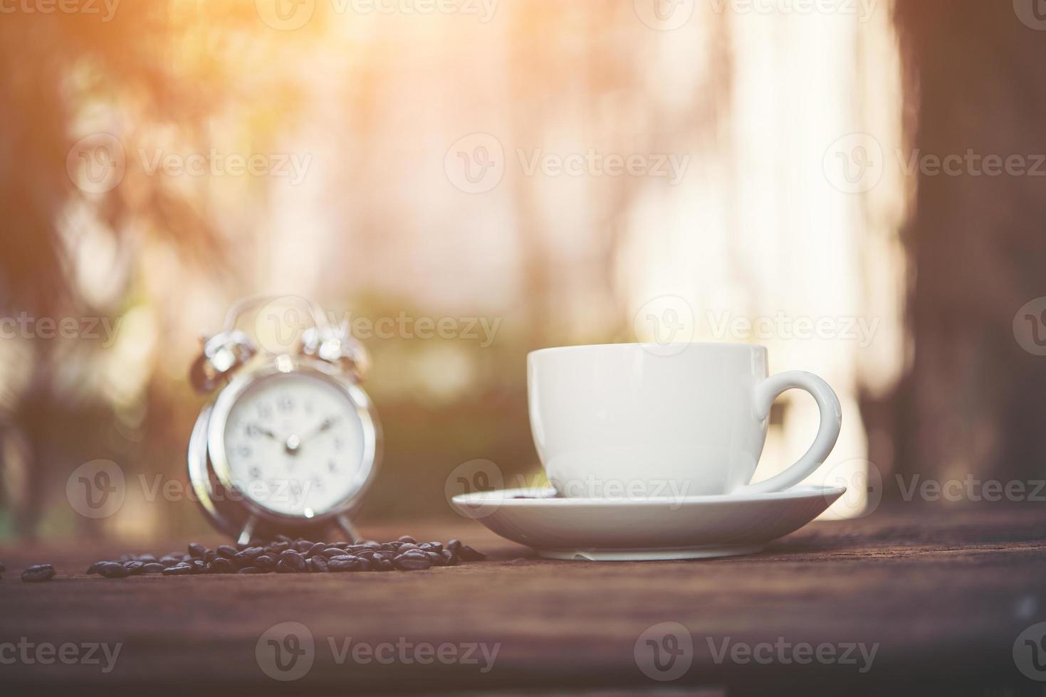 xícara de café com despertador no fundo natural da manhã foto