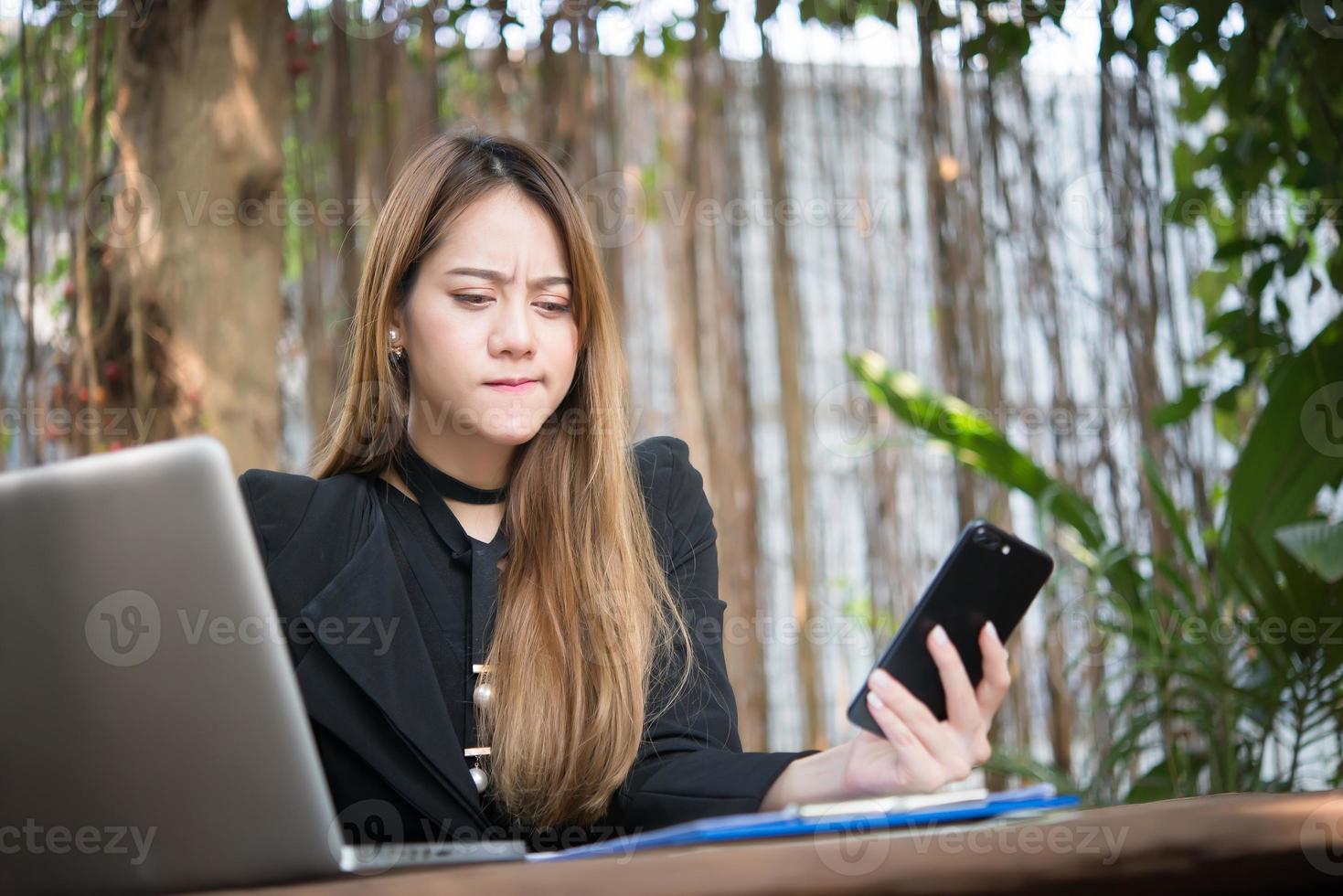 jovem empresária falando ao telefone enquanto está sentada em seu local de trabalho foto