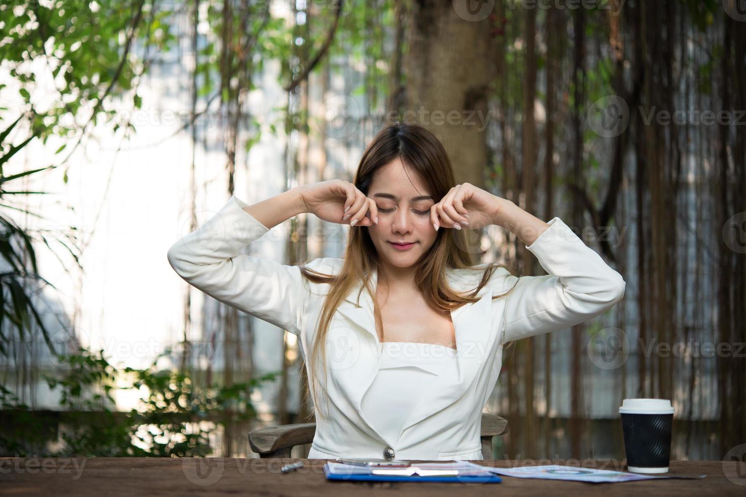 empresária se espreguiçando e bocejando no local de trabalho foto