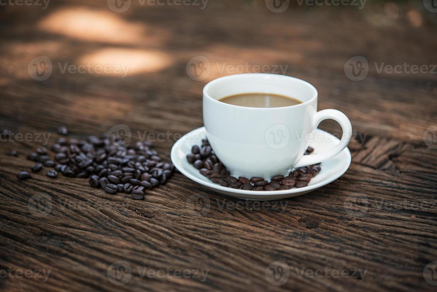 xícara de café e grãos de café na mesa de madeira foto