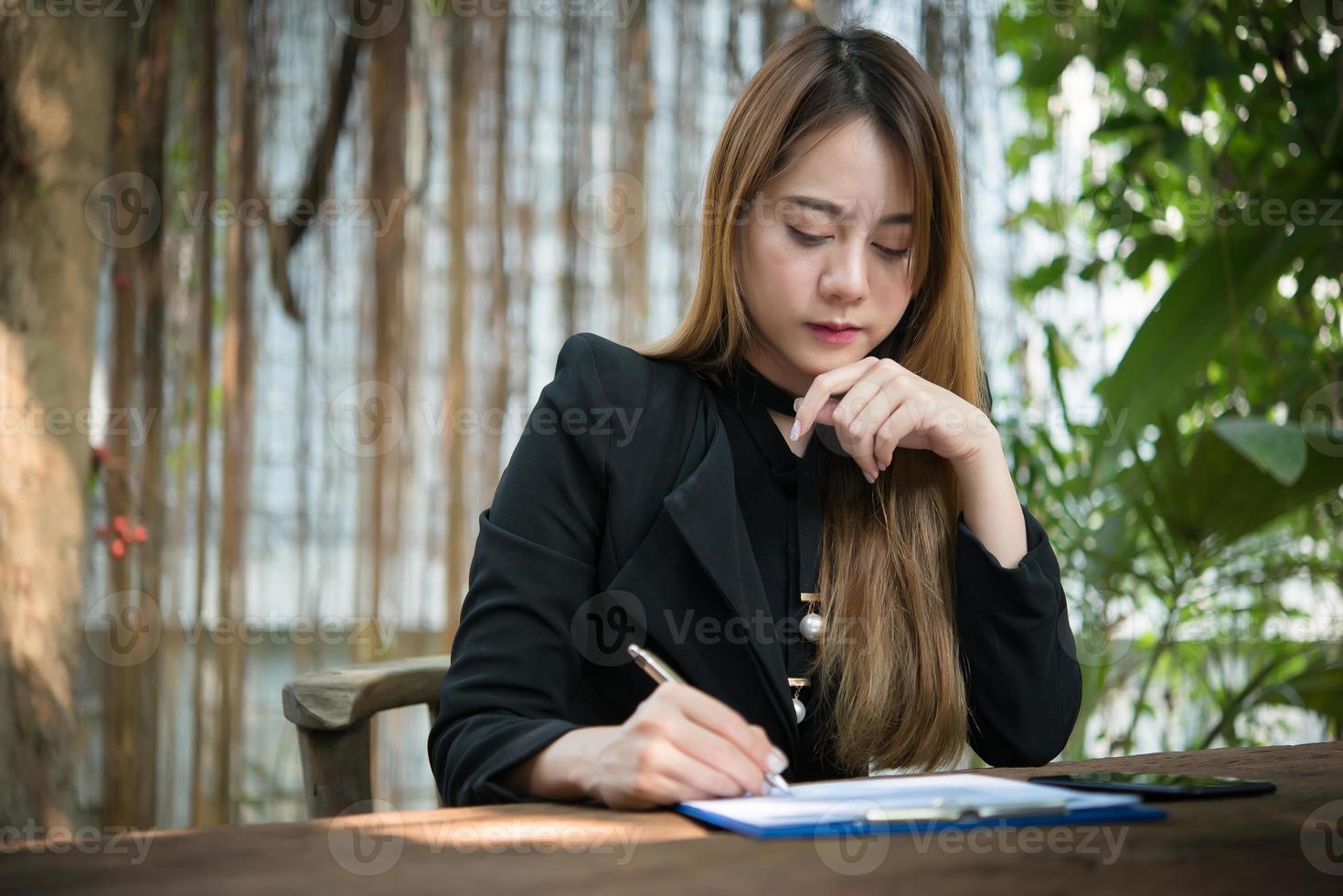 Mulher de negócios feliz assinando um documento na mesa trabalhando em casa foto