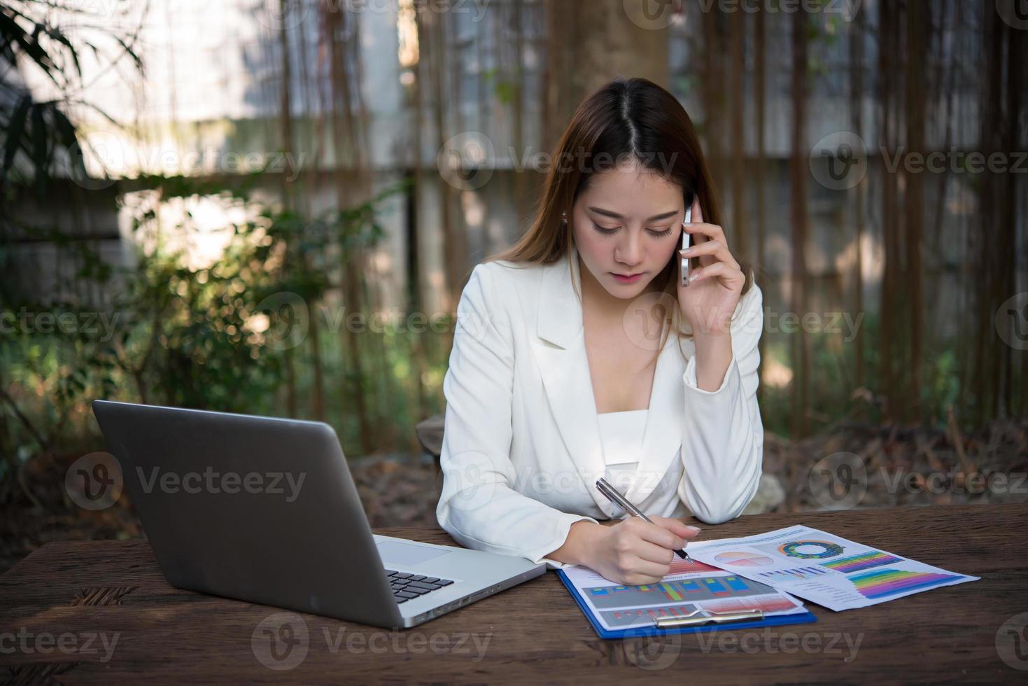 jovem empresária falando ao telefone enquanto está sentada no local de trabalho foto