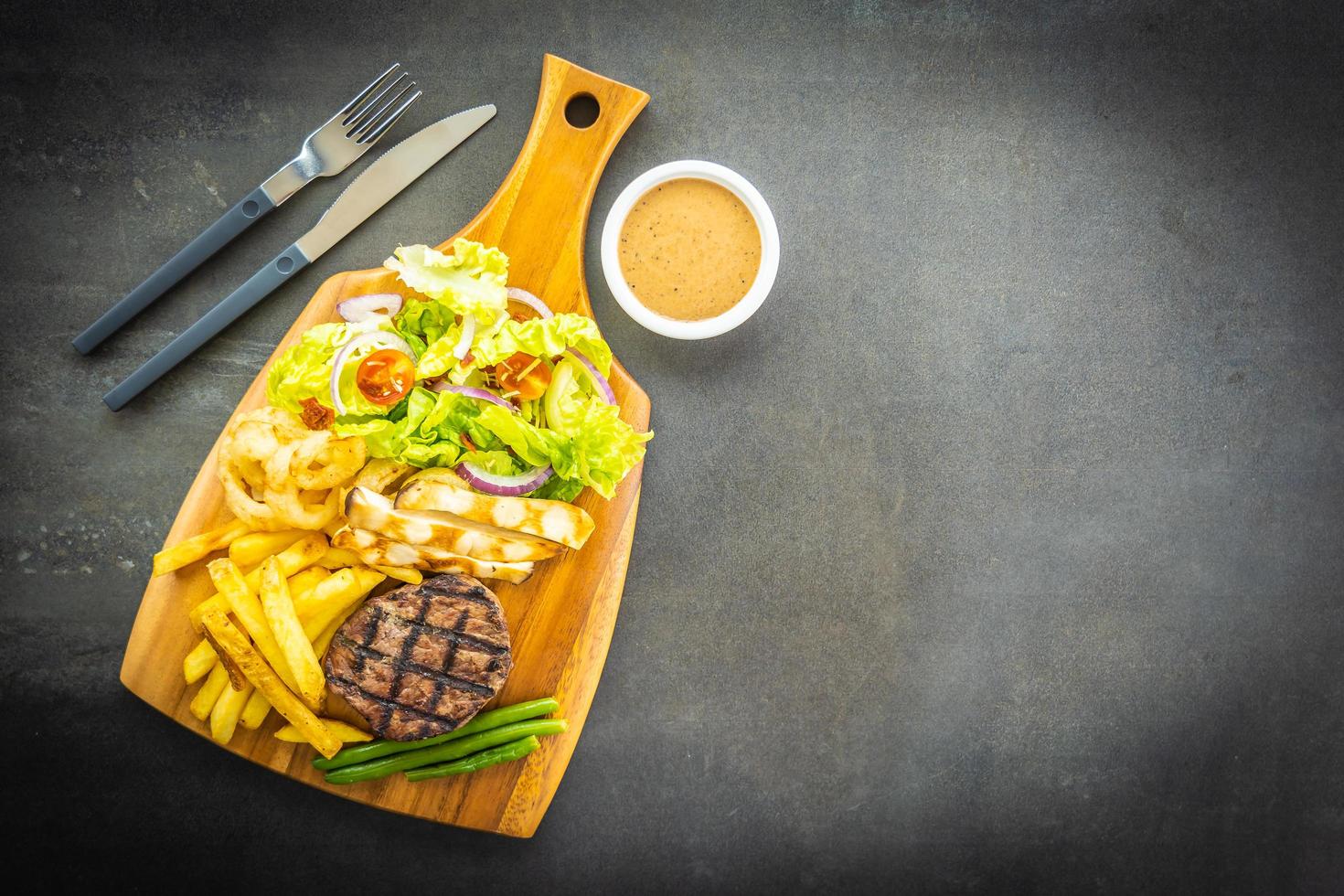 Bife grelhado com batata frita, molho e vegetais frescos foto