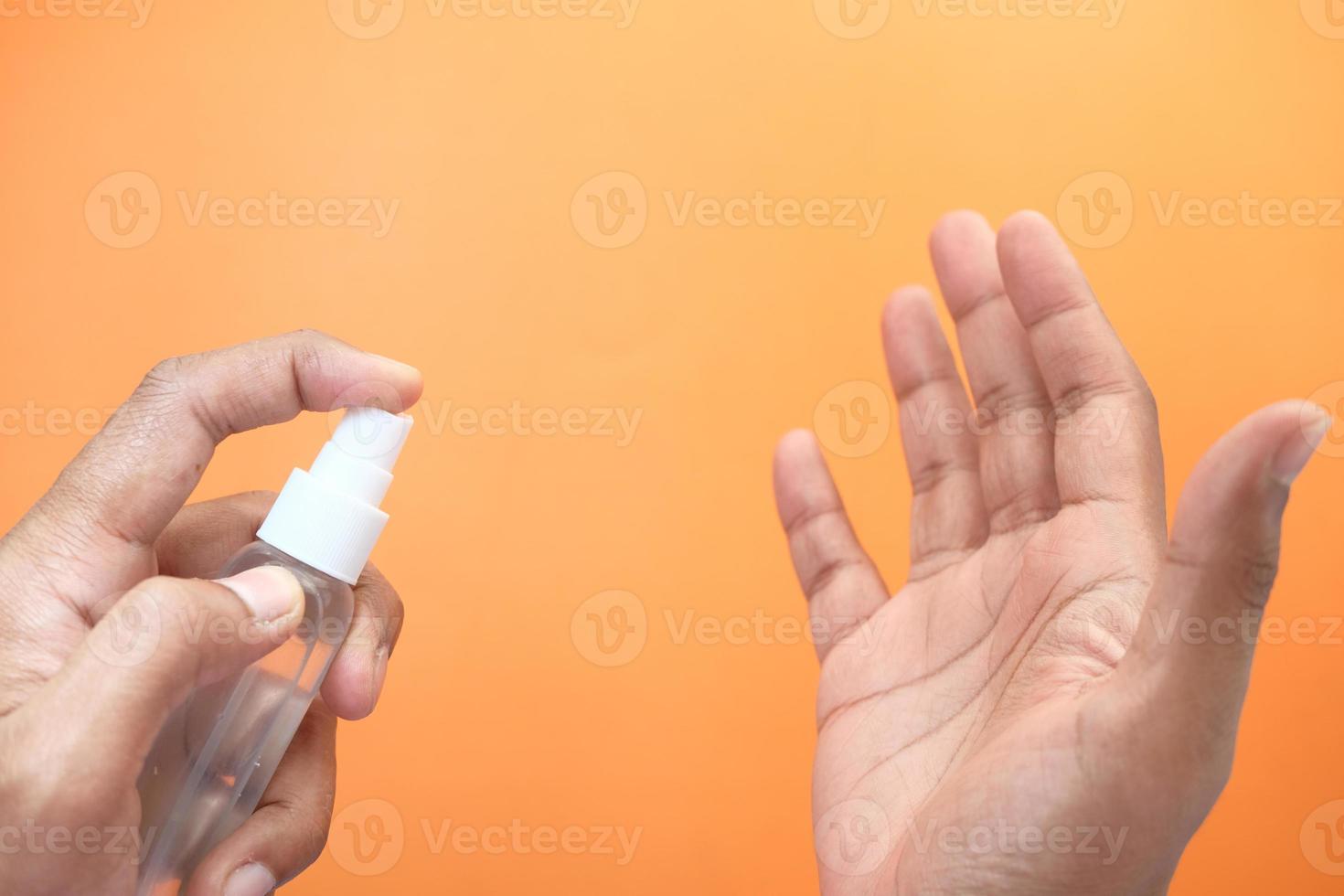 mão de homem usando spray desinfetante para as mãos foto