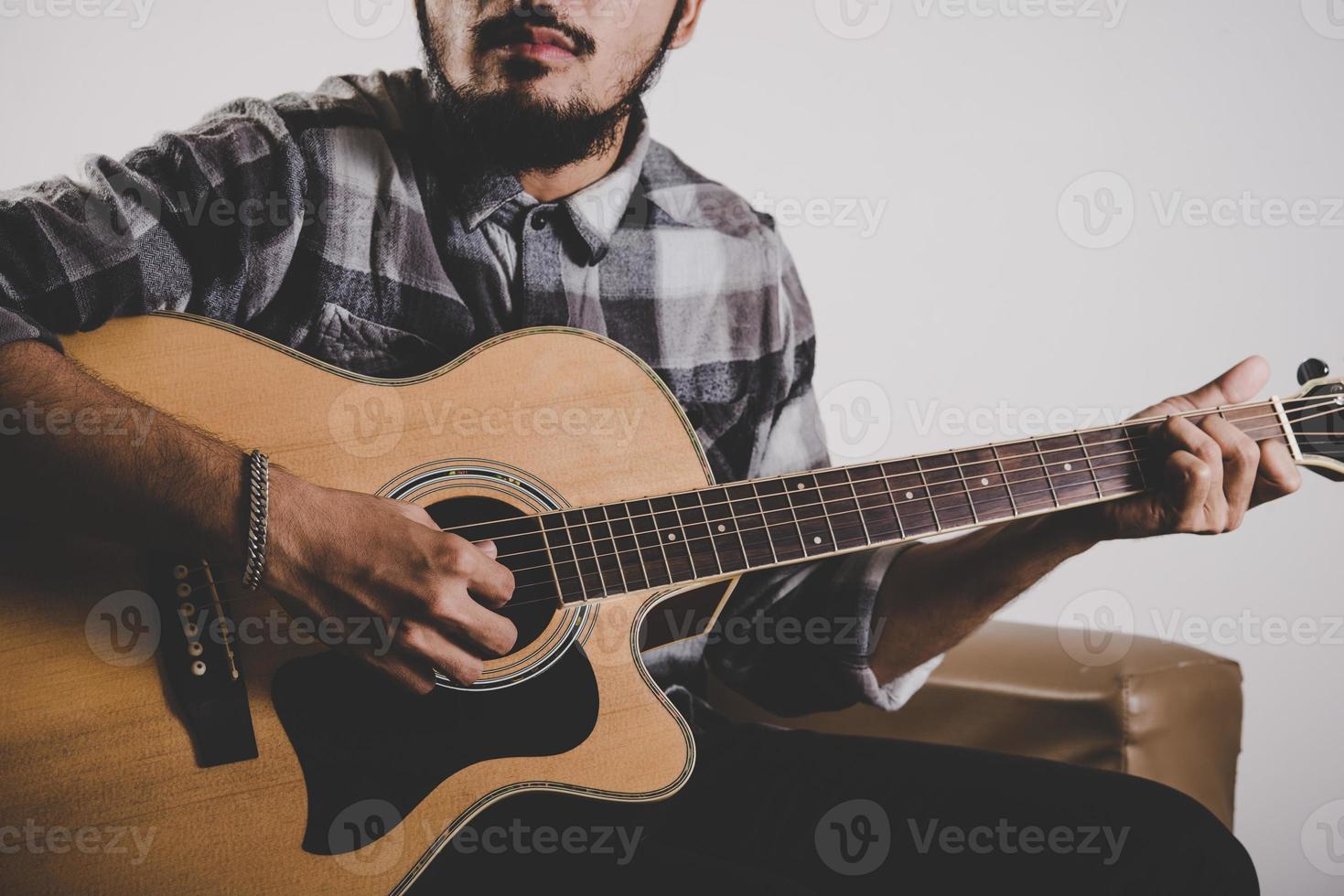 Feche a mão do homem barba hipster tocando guitarra foto