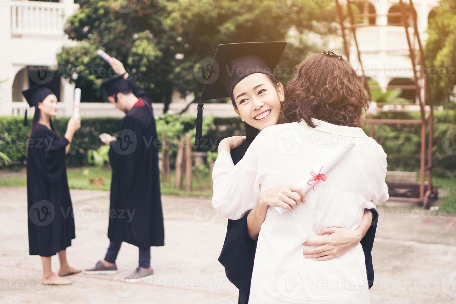 jovem graduada abraçando a mãe na cerimônia de formatura foto