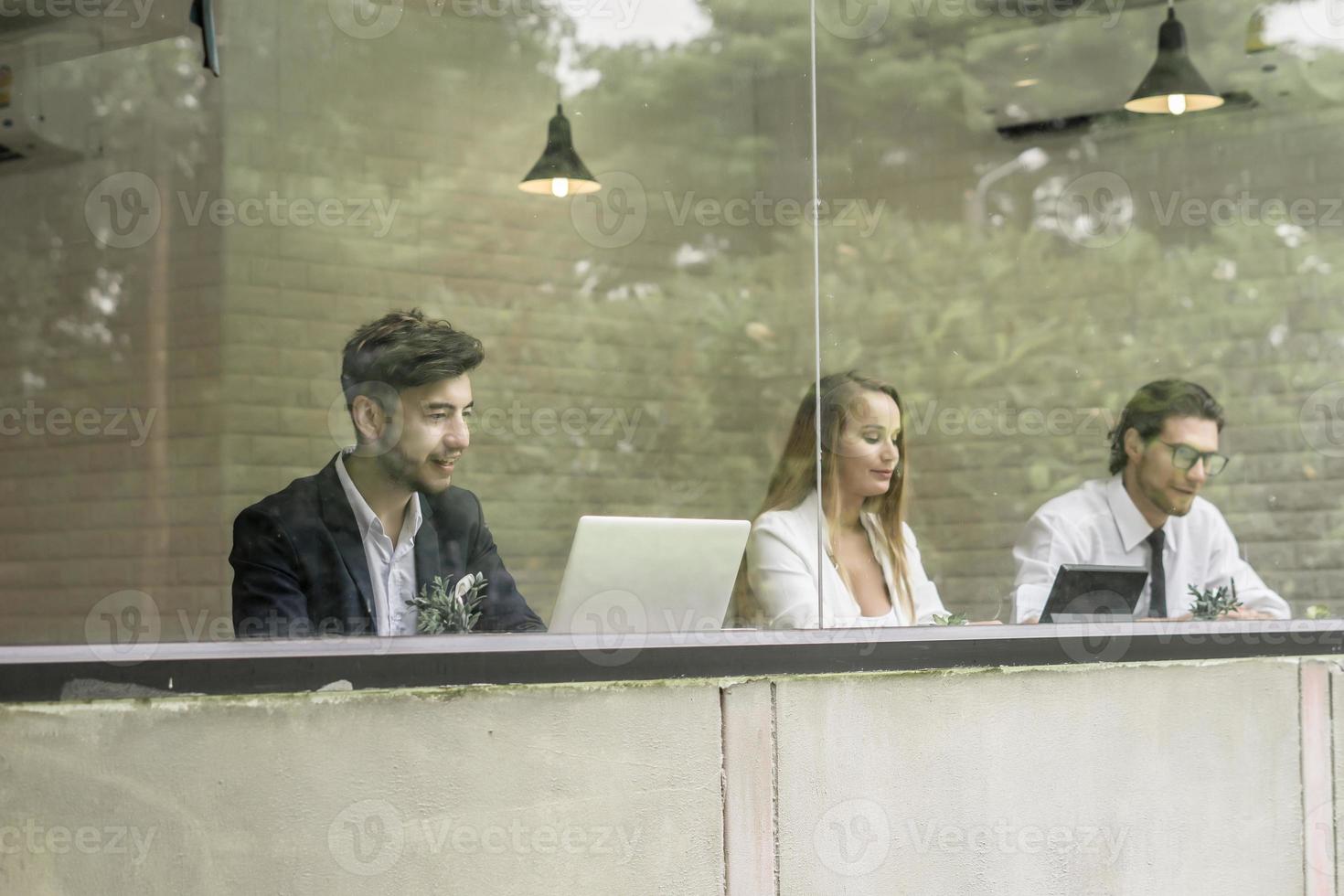 colegas felizes trabalhando juntos em laptops no escritório foto