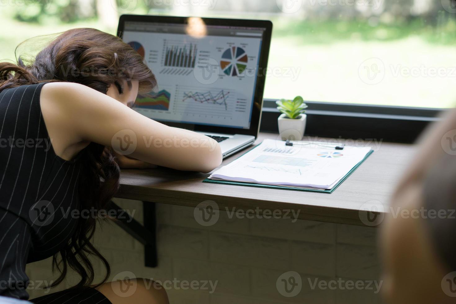 mulher de negócios adormece na mesa em frente ao seu laptop foto