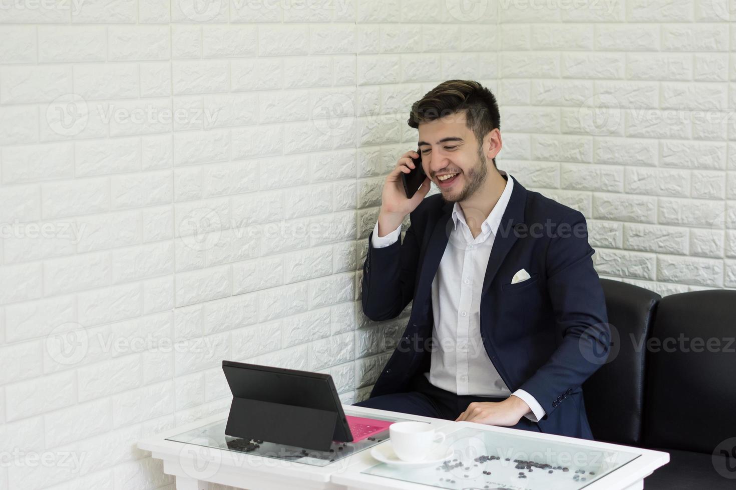 jovem empresário usando smartphone enquanto trabalha em seu laptop no escritório foto