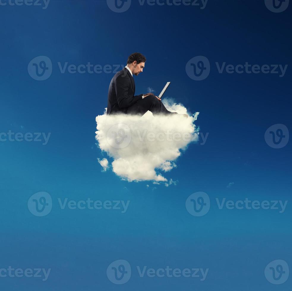 homem de negocios conectado com dele computador portátil sobre uma nuvem. conceito do social rede e Internet vício foto