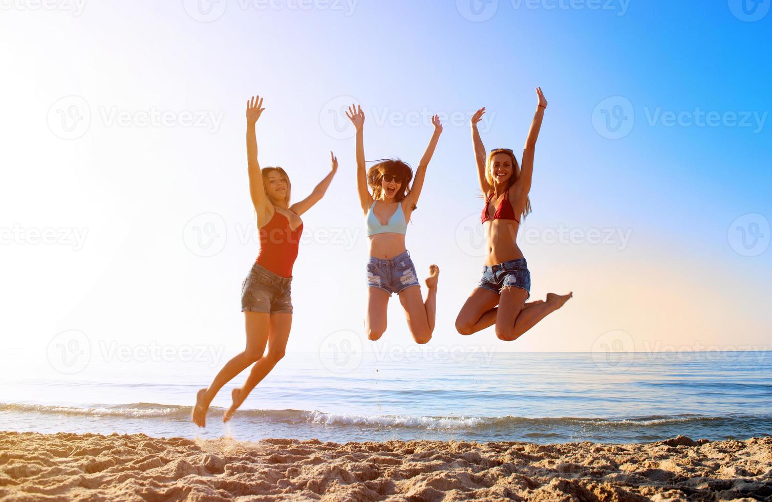 feliz sorridente amigos pulando às a de praia foto