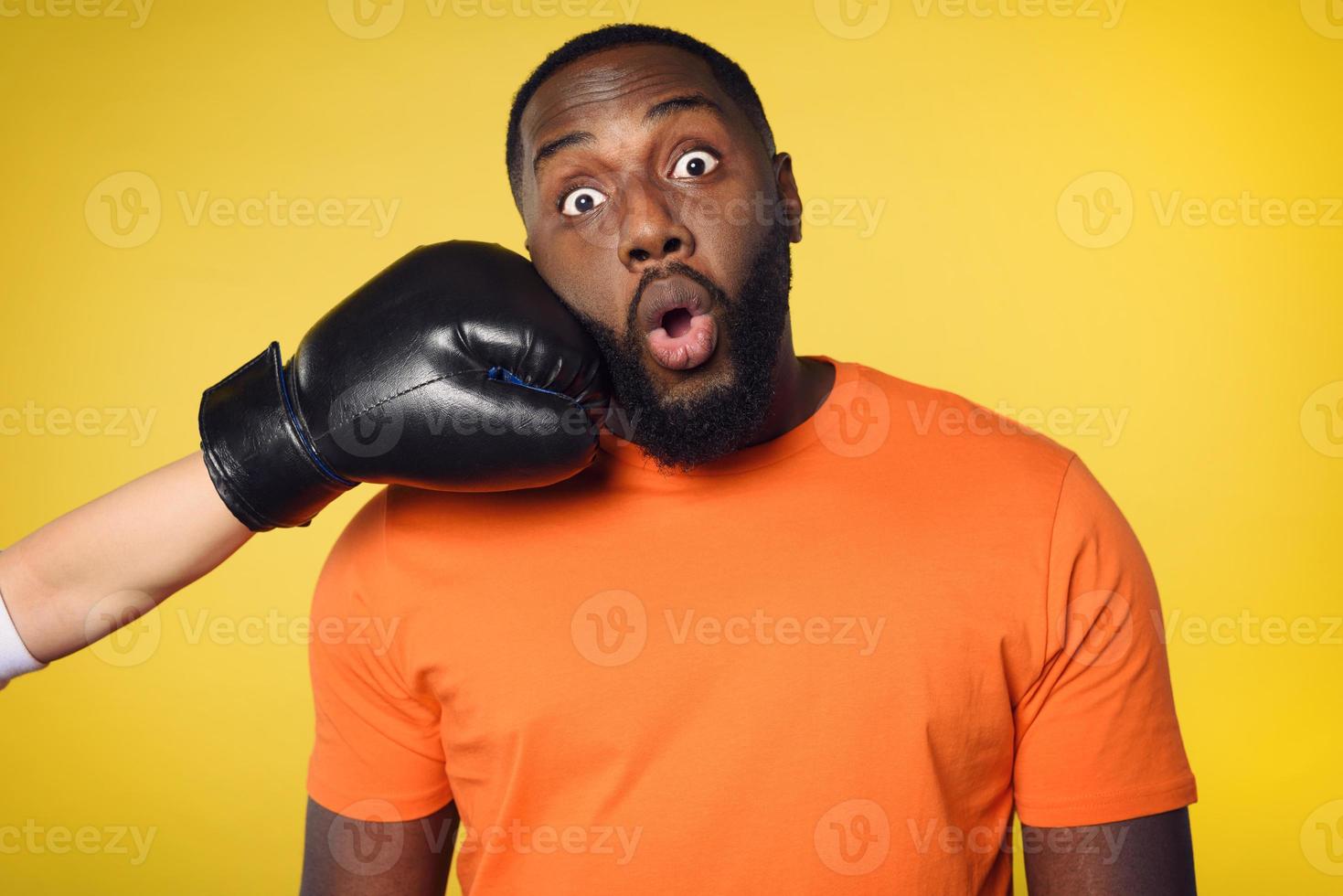 chocado Preto homem recebe uma soco a partir de alguém. amarelo fundo foto