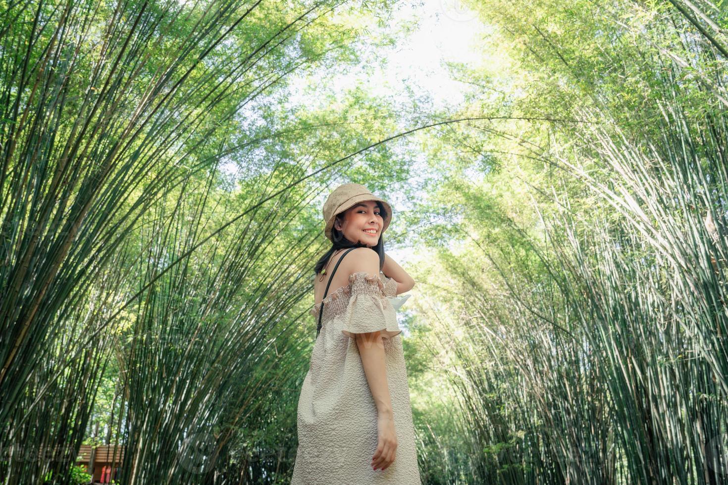 jovem ásia mulher vestindo chapéu em pé dentro bambu floresta às campo foto