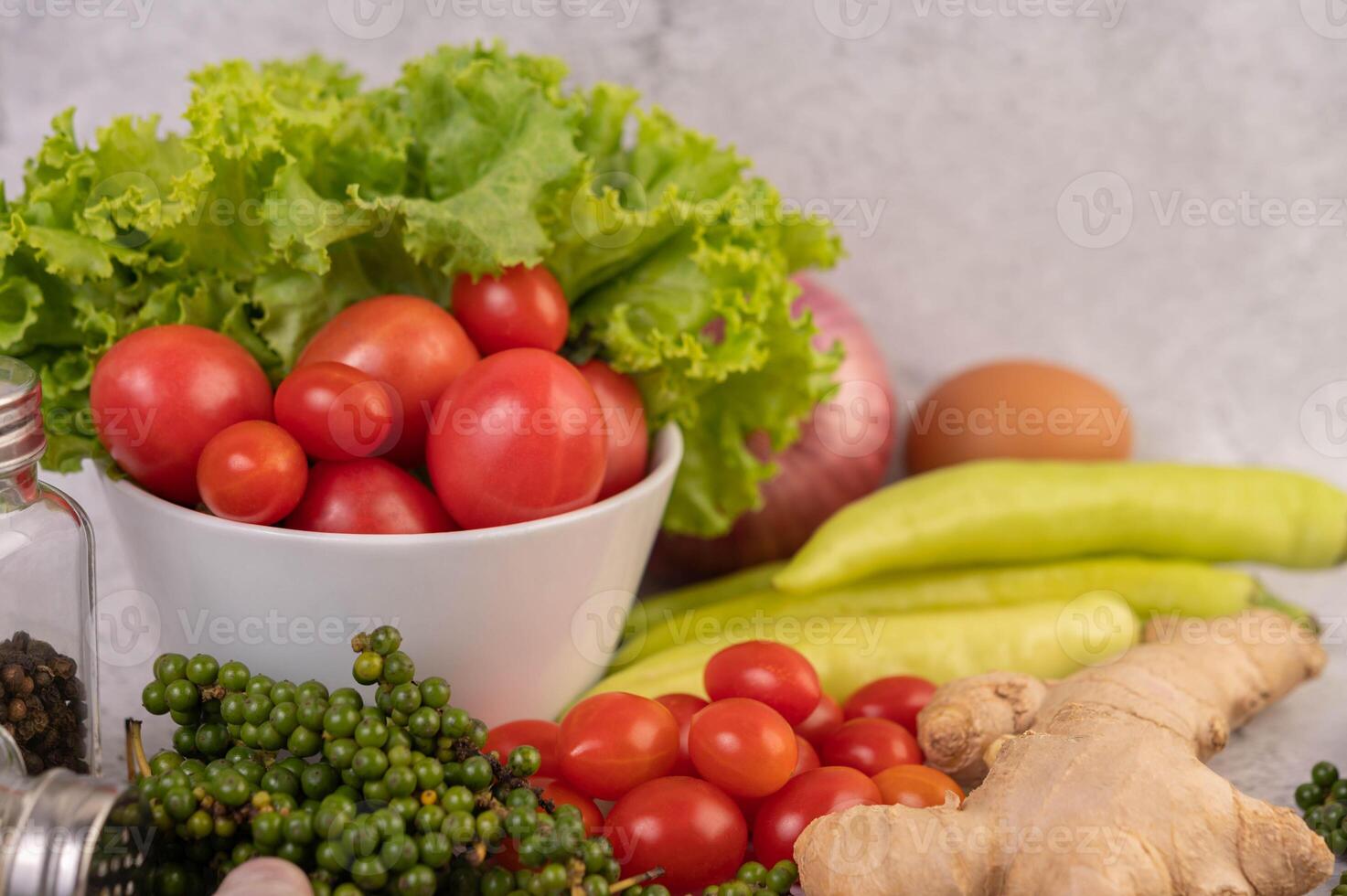 foto alface e tomates dentro uma branco copo com fatiado cebolas e fresco pimentas em a cimento chão.